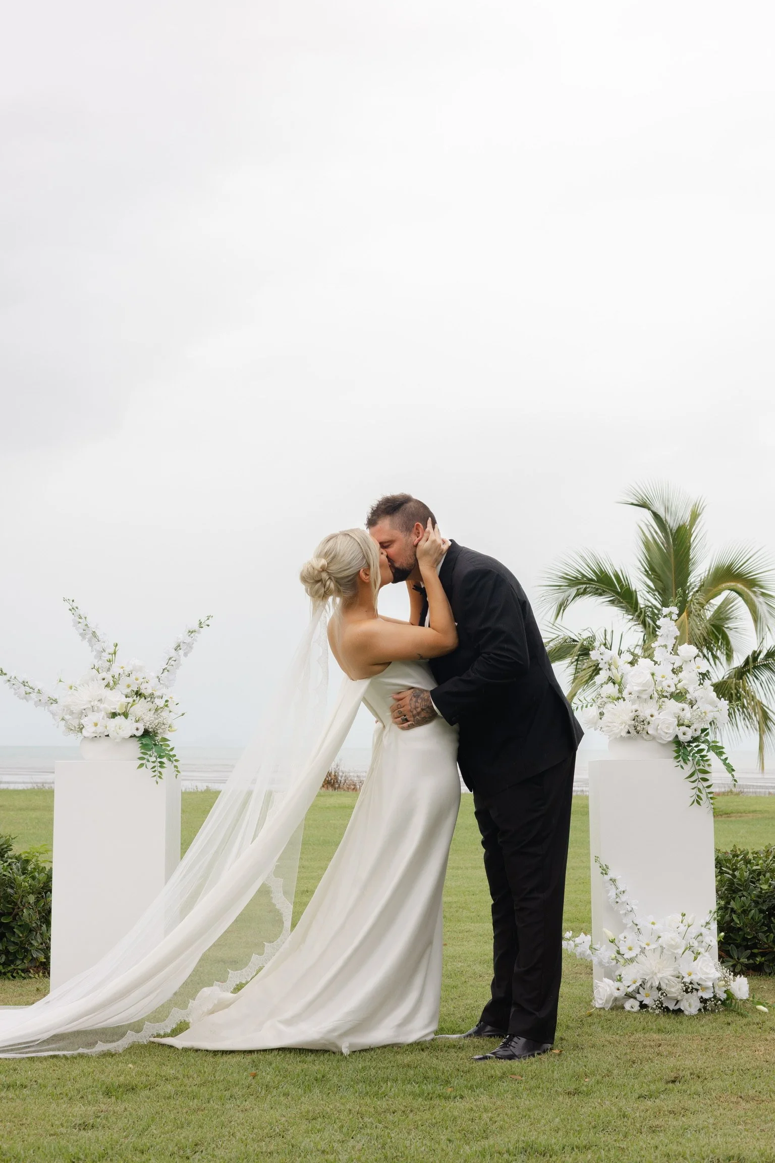 Luxury wedding ceremony styling featuring a white floral arbour and aisle styling by Salt & Silk Collective in Airlie Beach, Whitsundays.