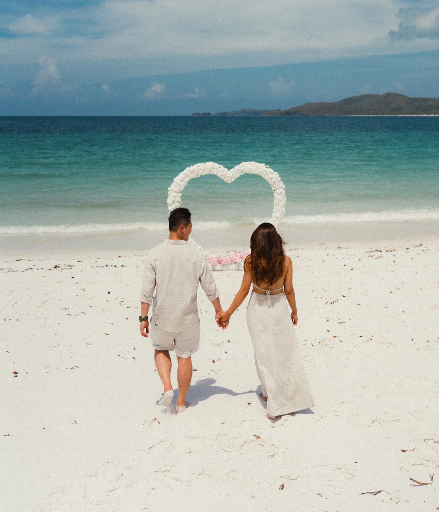White rose heart beach proposal setup in Airlie Beach and the Whitsundays featuring luxury oceanfront engagement styling, romantic florals and proposal package by Salt & Silk Collective