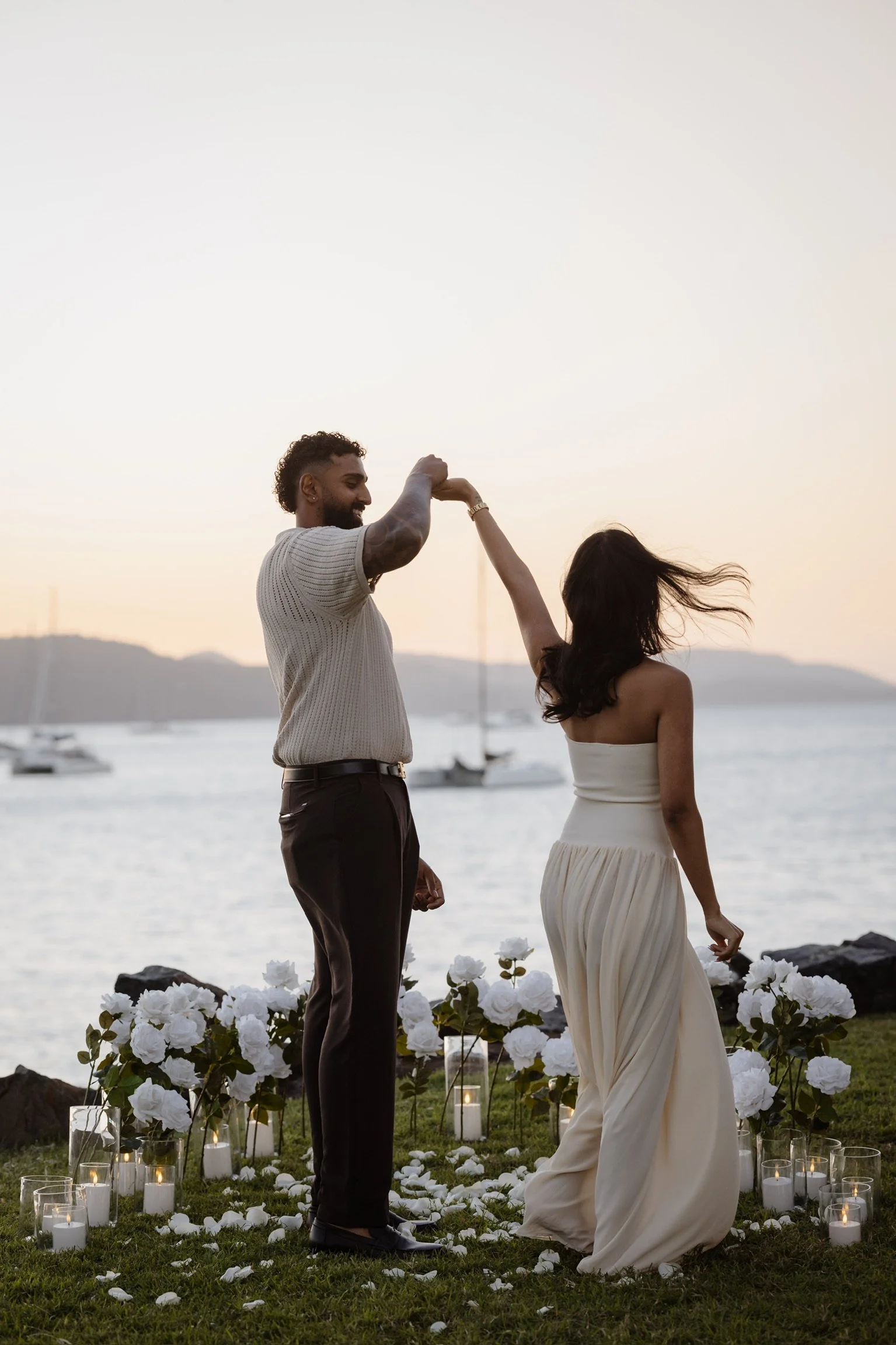 Romantic waterfront proposal setup in Airlie Beach and the Whitsundays featuring white florals, candles, rose petals and luxury engagement styling by Salt & Silk Collective