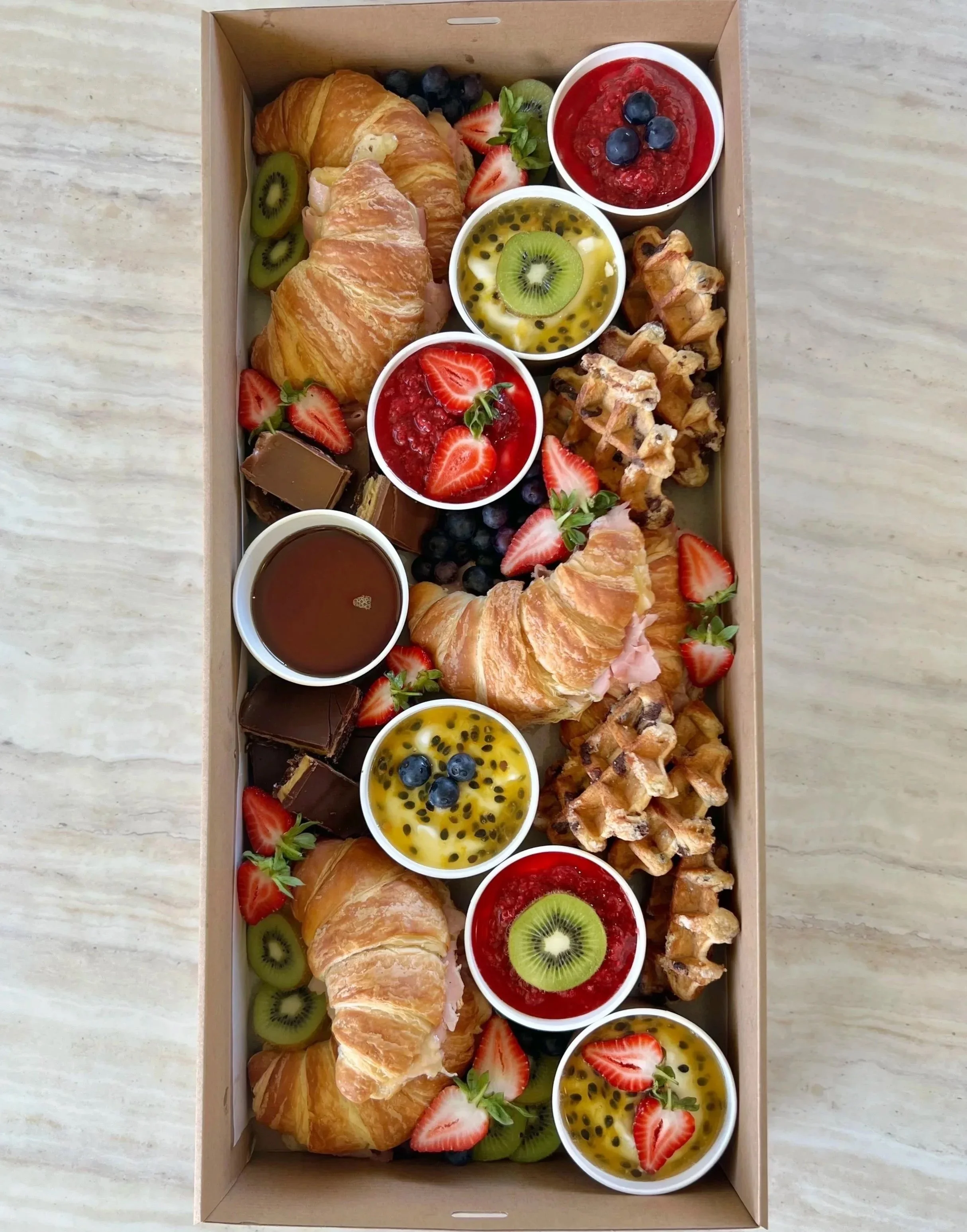 Luxury breakfast boxes with croissants, yoghurt pots, fresh fruit and pastries by Salt & Silk Collective, offering breakfast catering and grazing boxes in Airlie Beach and the Whitsundays.