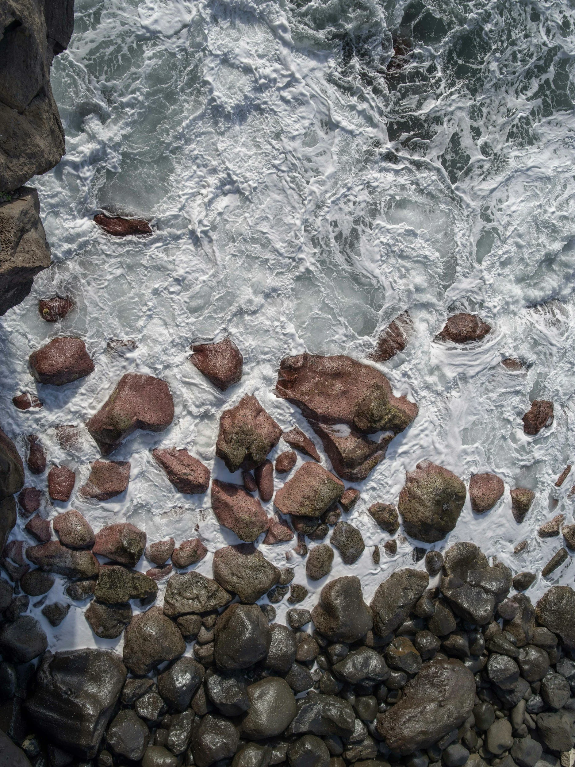 Ocean waves crashing over rocks, representing the process of moving past surface-level stress to address deeper root causes in therapy.