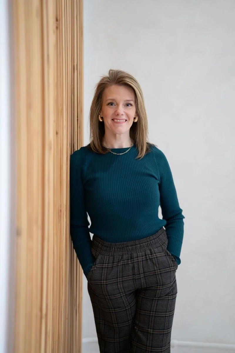 Jennifer Weinmann, LMFT, a licensed couples and individual therapist based in Eatonville, Washington, smiling and standing against a wood-paneled wall.