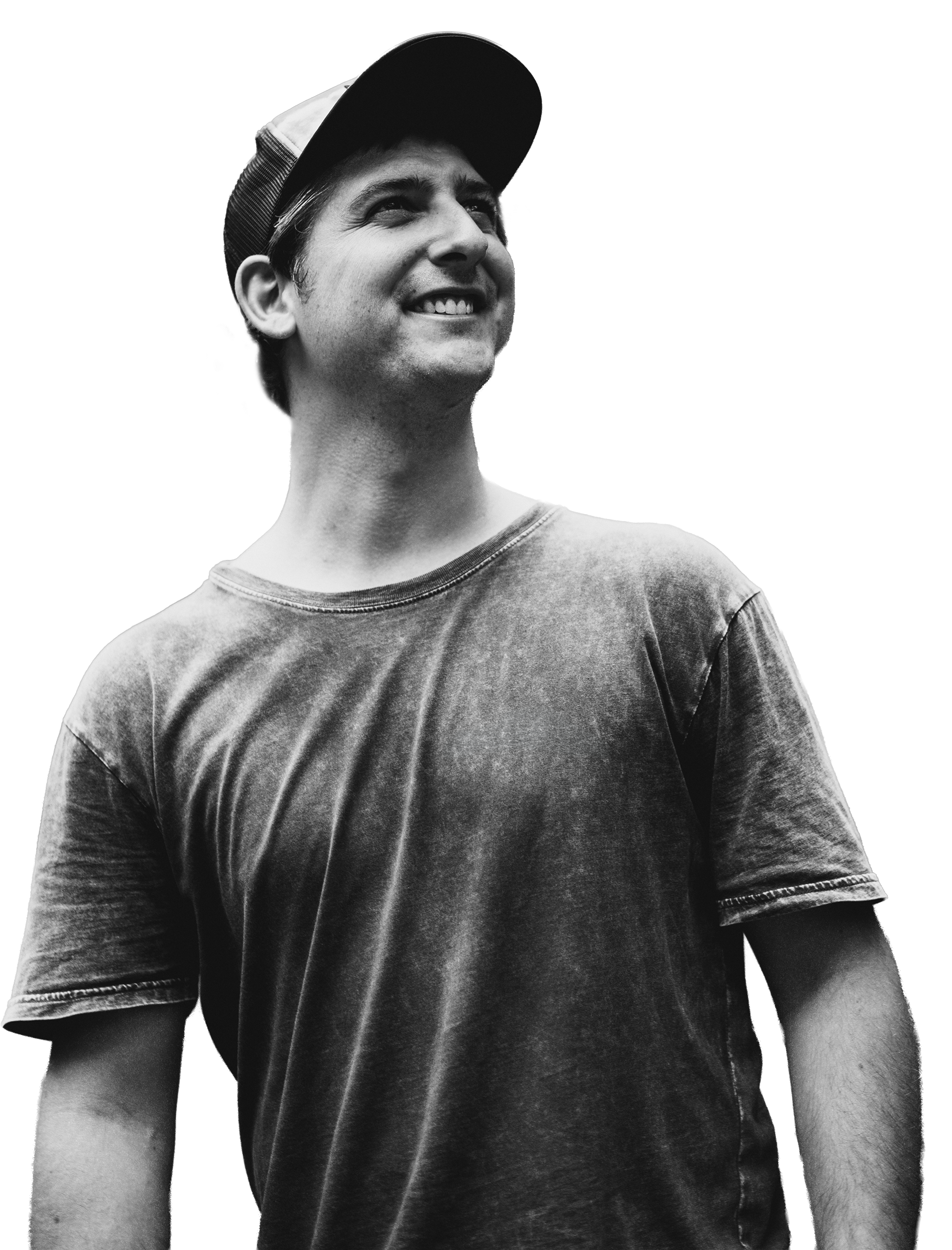 Black and white photo of a young man smiling, wearing a baseball cap and a t-shirt.