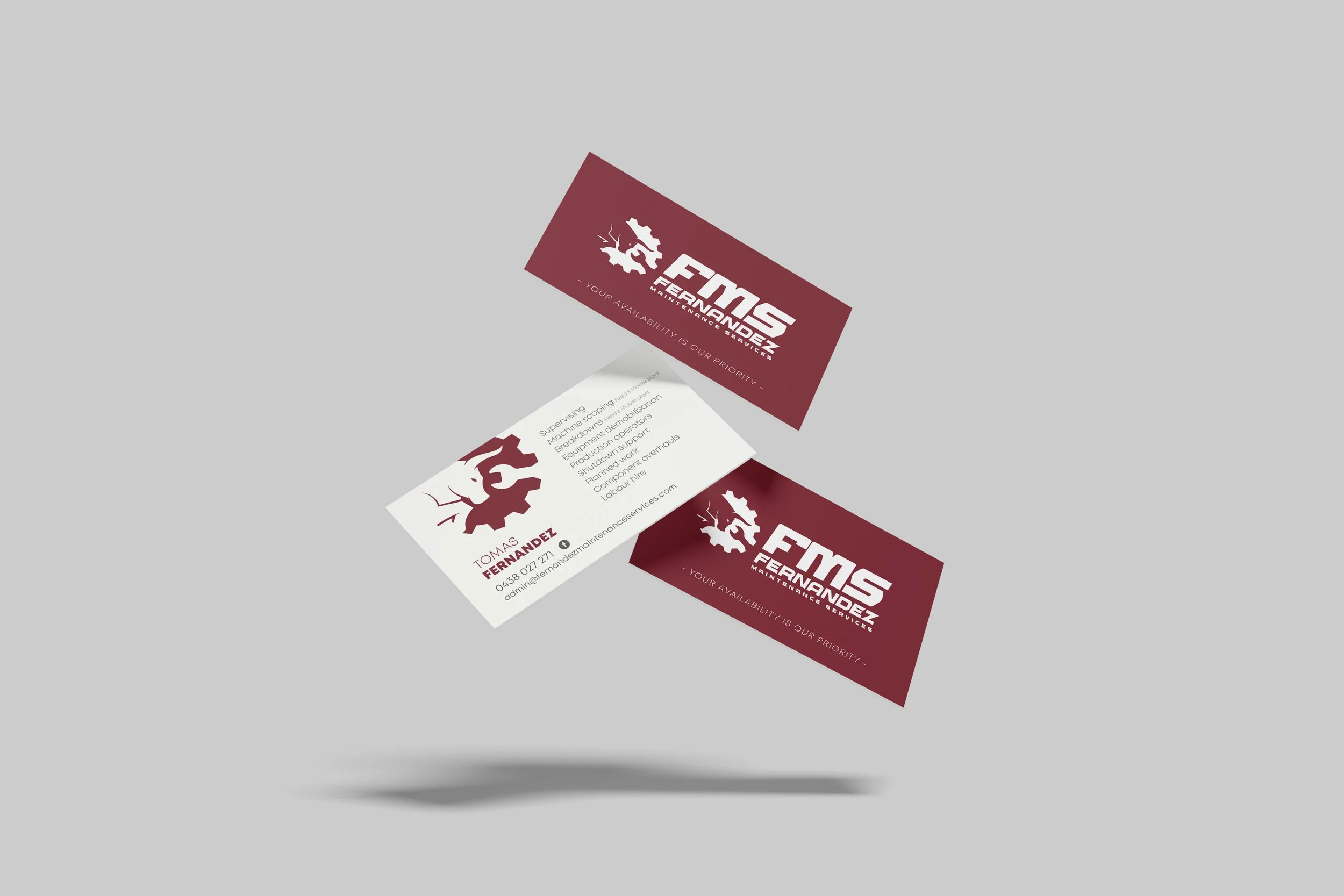 Business cards for Tomas Fernandez with a dark red background, white and red text, and a gear logo.