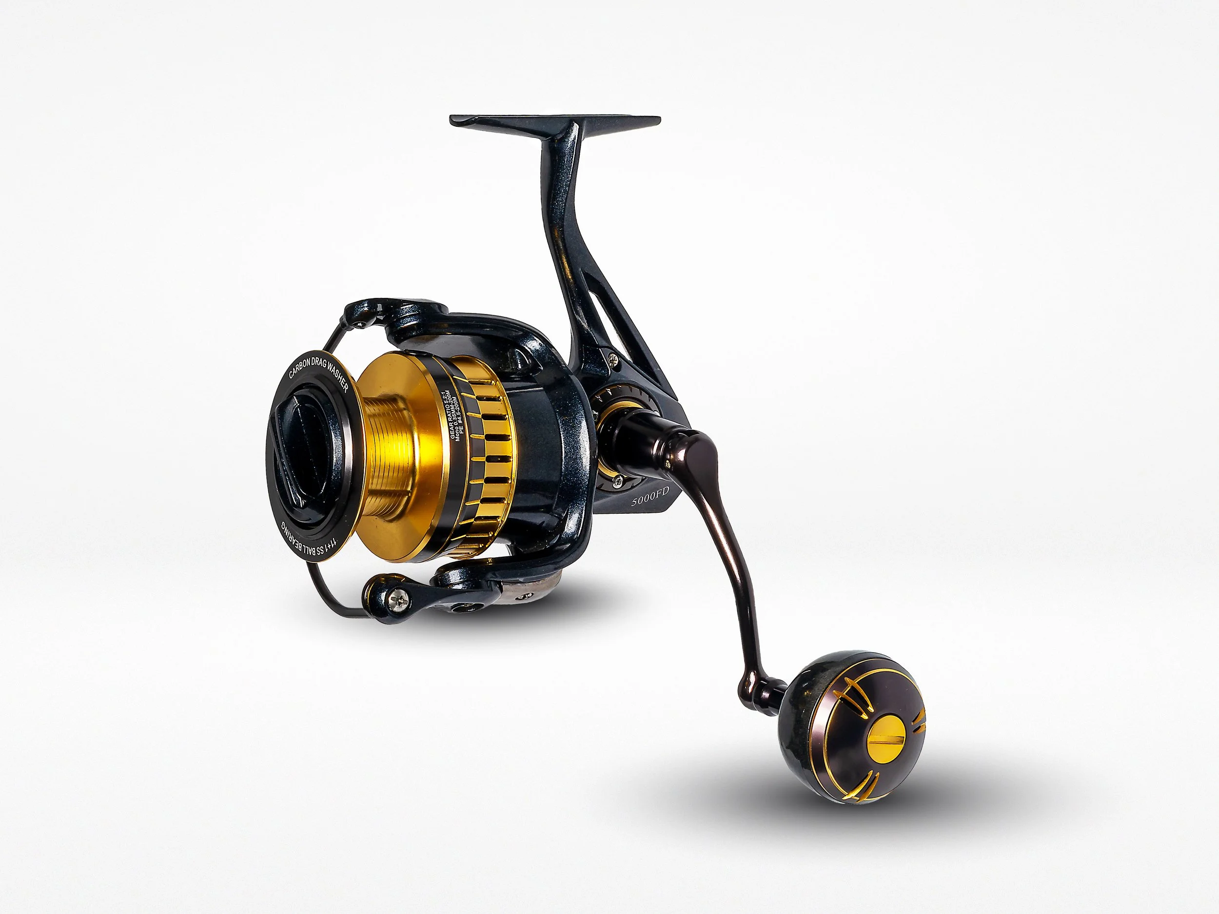 A black and gold fishing reel with a handle, set against a plain white background.