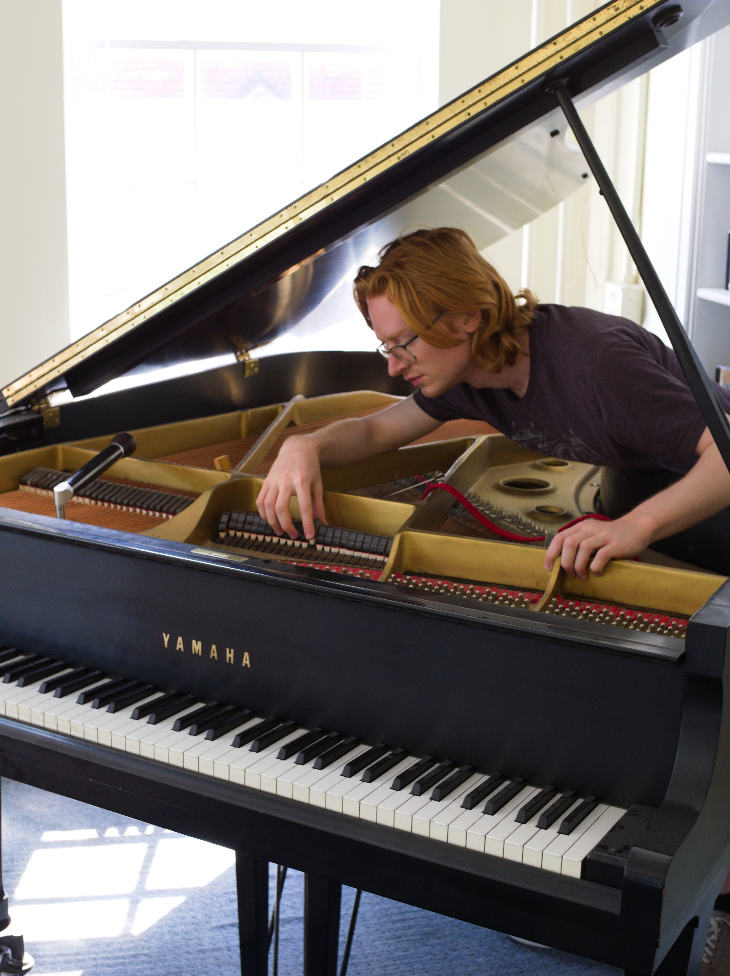 Brendan Coller examining dampers in a Yamaha grand piano