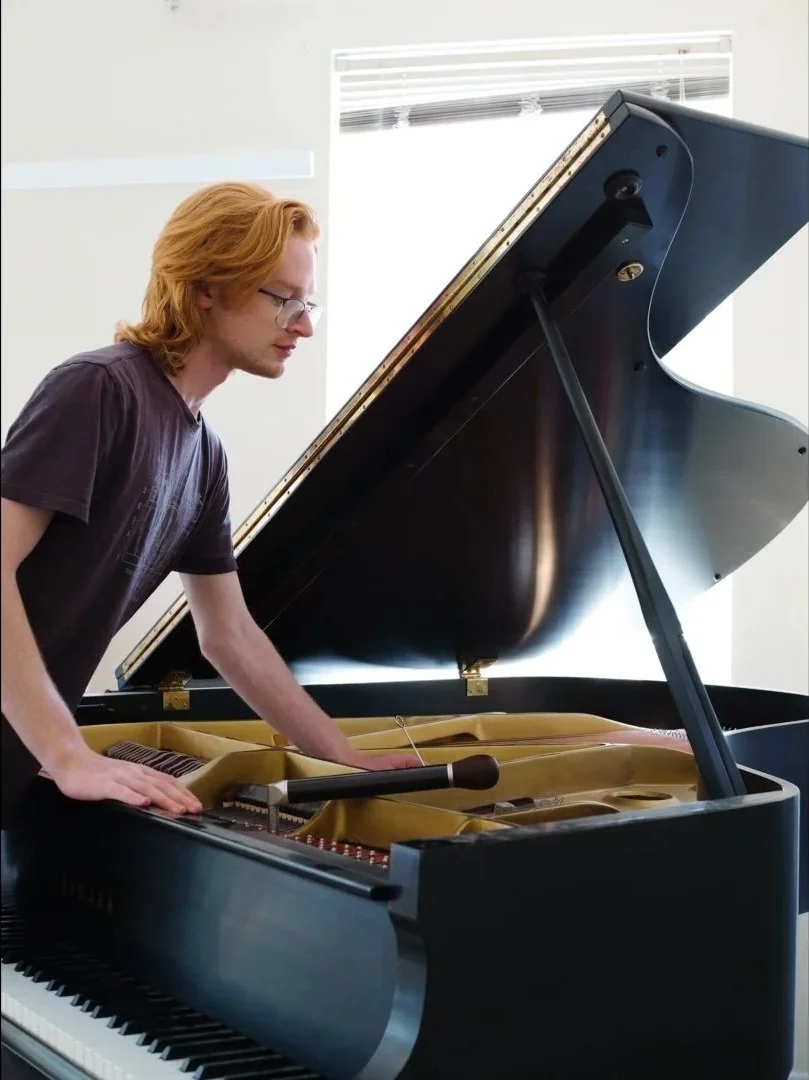 Brendan Coller adjusting a piano mute while tuning a Yamaha grand piano