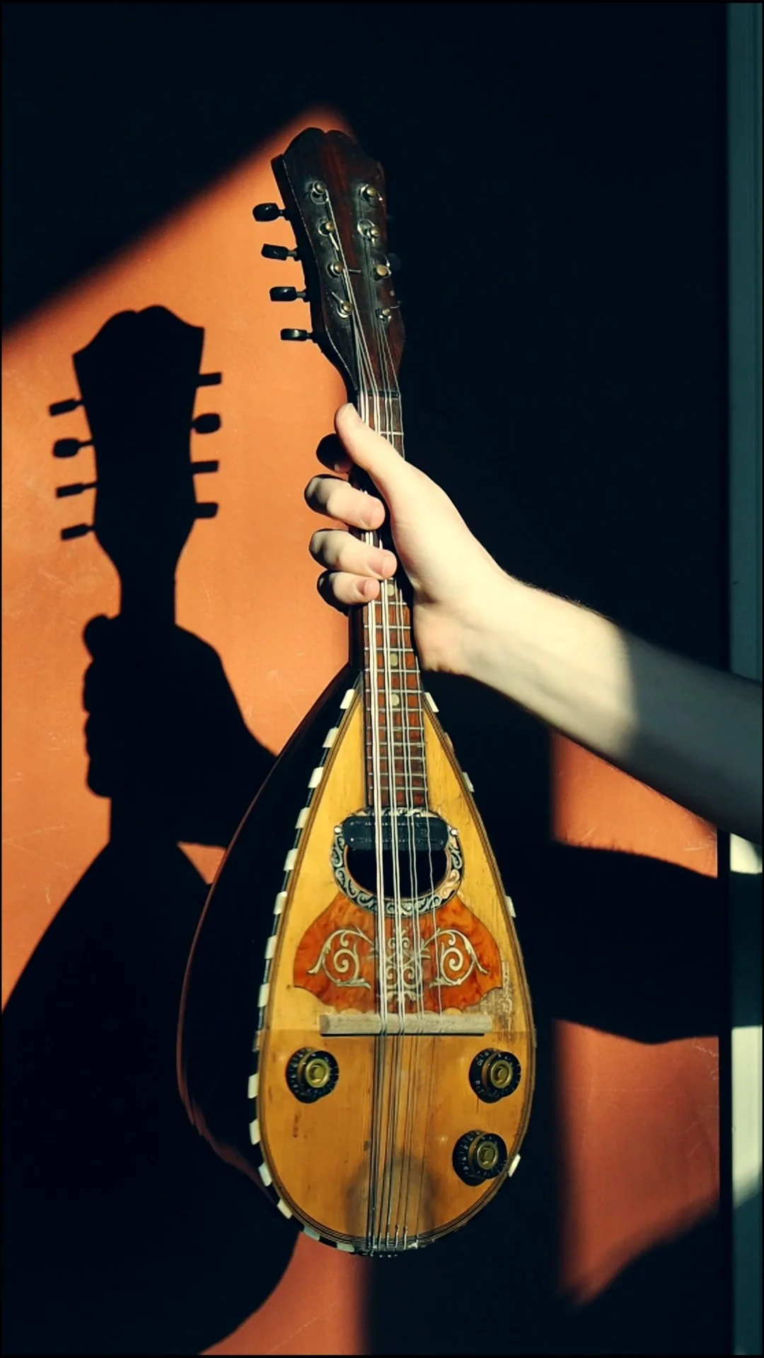 Brendan Coller holding an electric mandolin he built