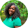 Beautiful black woman  with a  sisterlocks braid-out   smiling outdoors in nature, wearing a teal top.