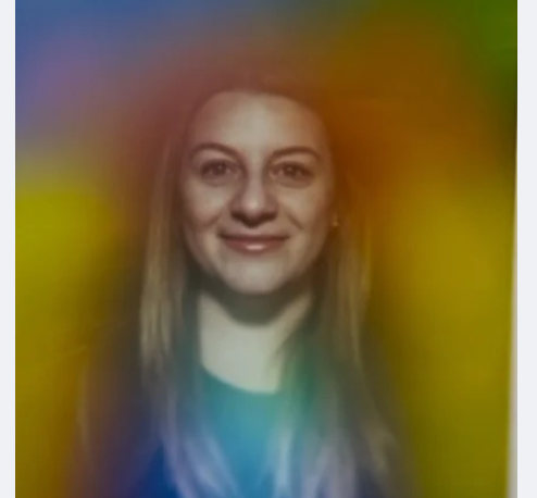 Smiling woman with long hair, surrounded by a colorful rainbow blur.