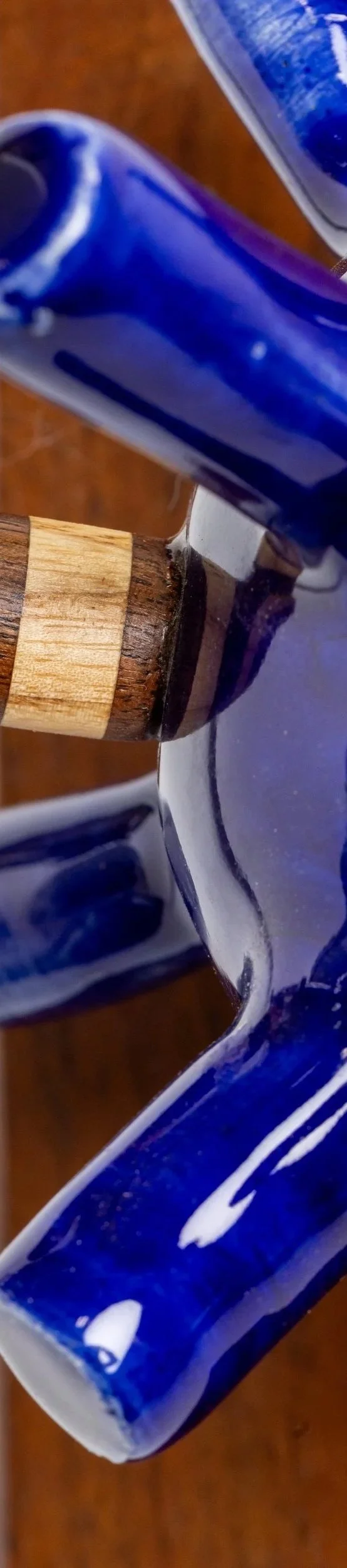 Close-up of a blue ceramic mug with a wooden handle resting on a wooden surface.