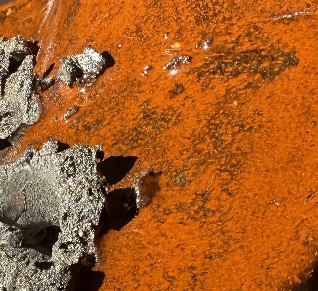 Close-up of a rusty metal surface with patches of peeling paint and corrosion.