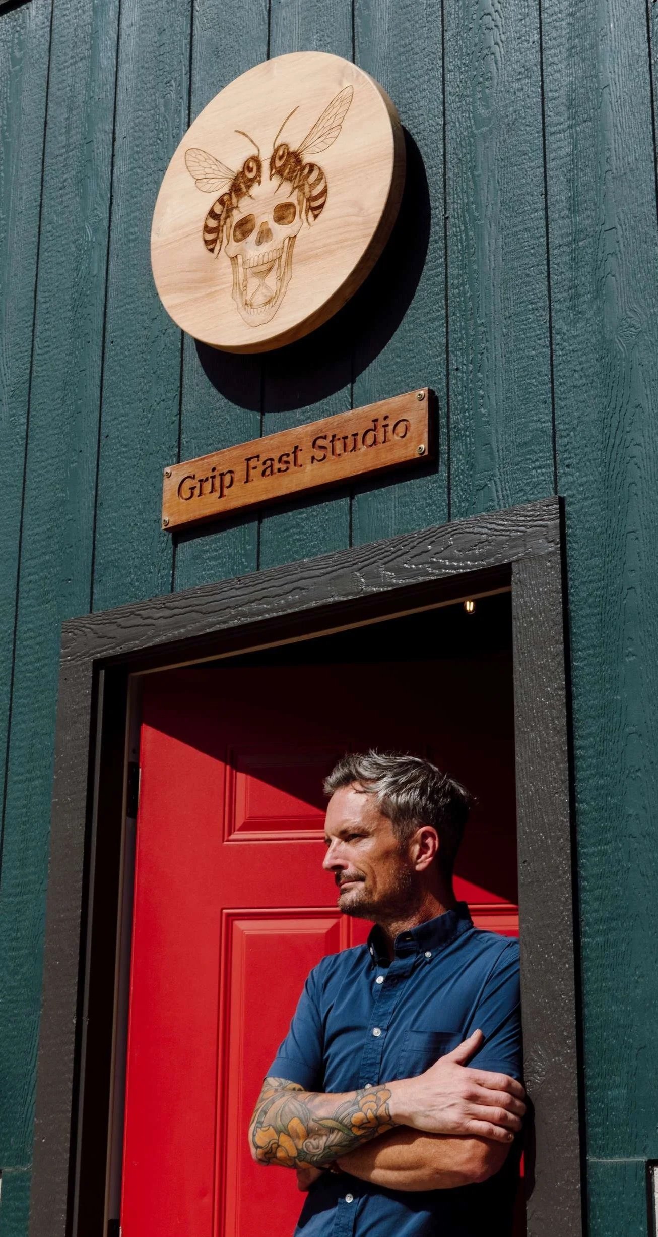 Artist Brendan Bishop at the red door of Grip Fast Studio, Omaha, Nebraska.