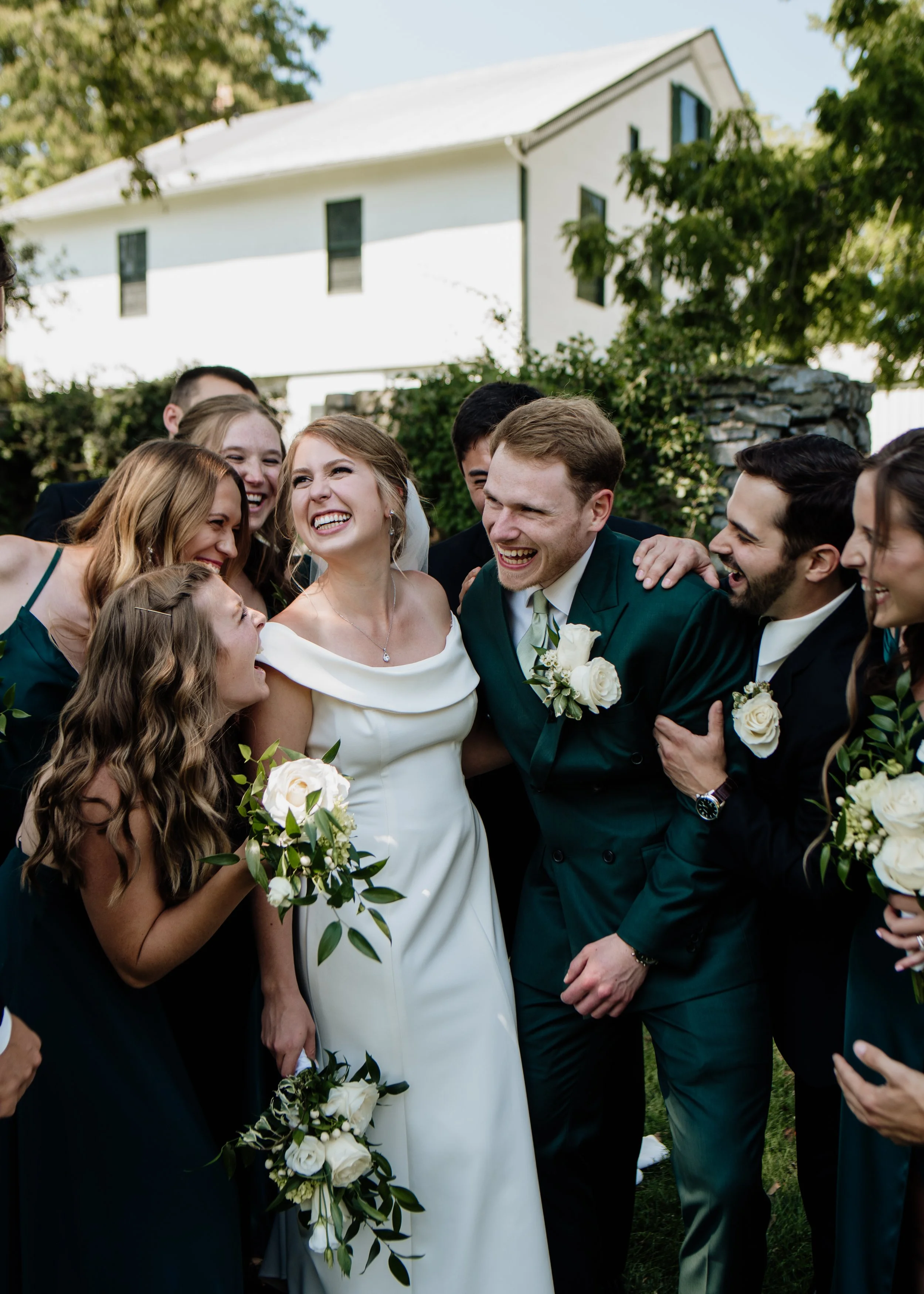 A bride and groom at a wedding surrounded by friends and family, all smiling and celebrating outdoors.