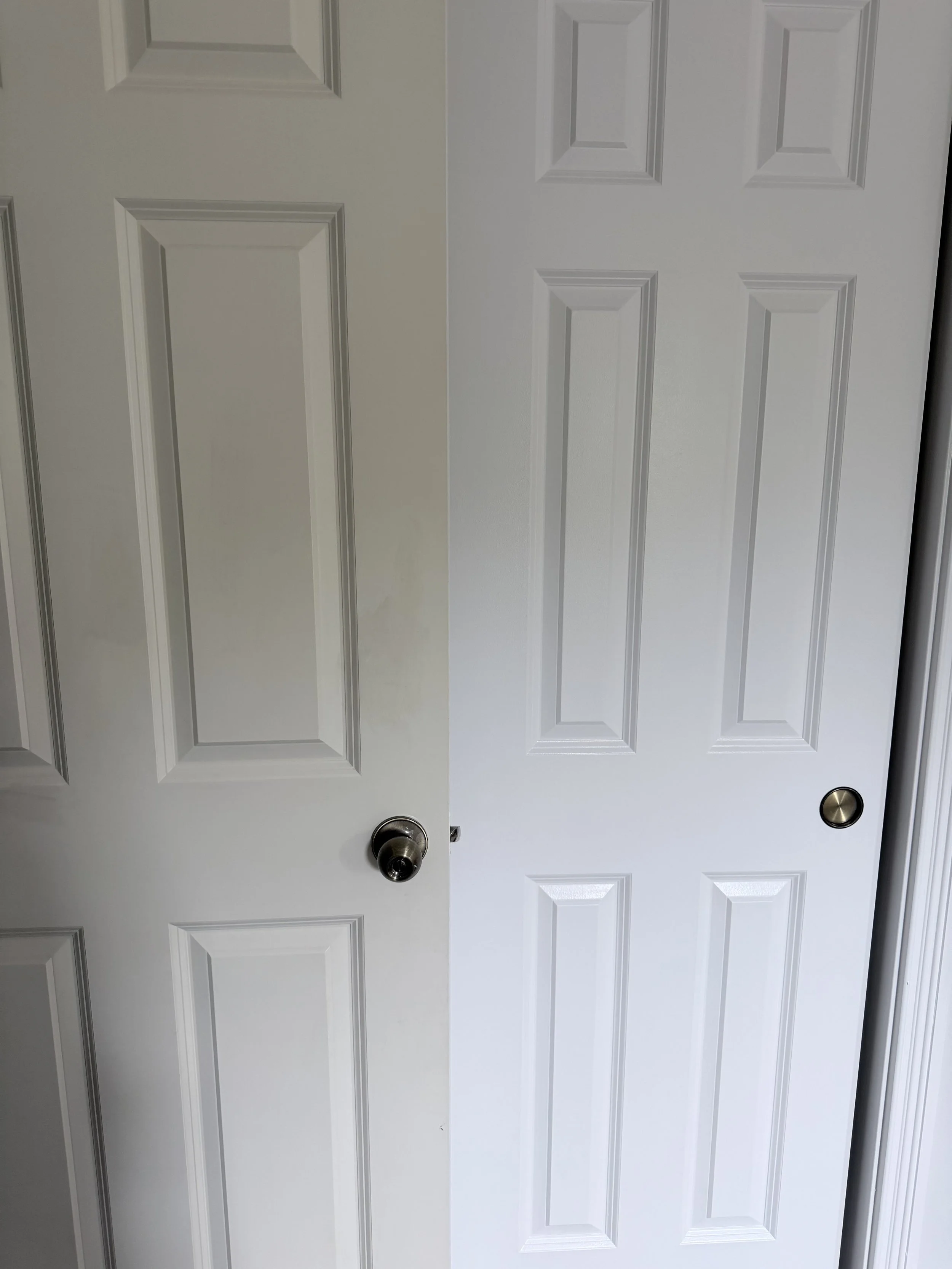 A white six-panel door with a brushed nickel doorknob.