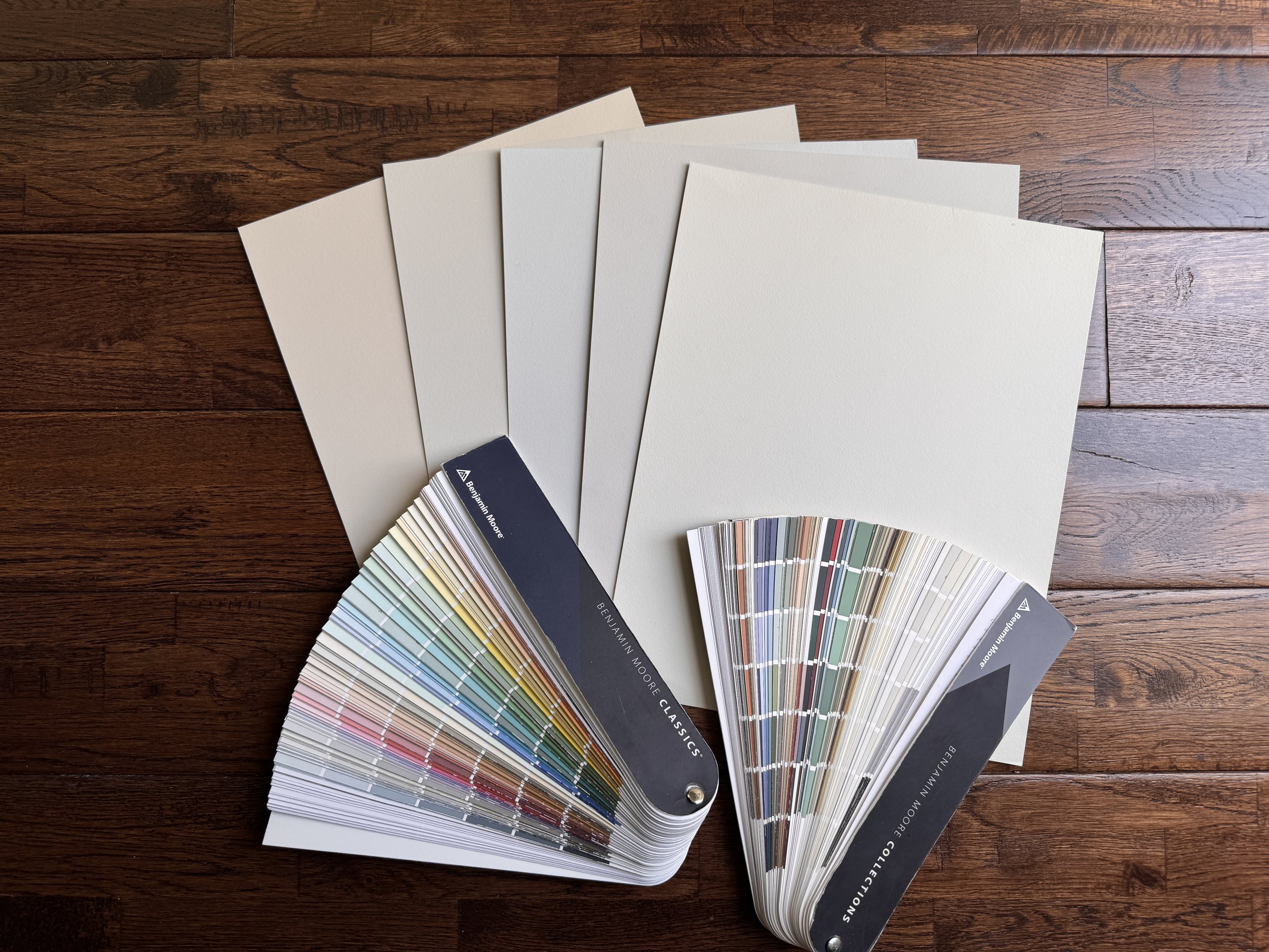 Color swatch fan deck featuring various shades and hues, with a set of five paint or color sample cards on a wooden surface.