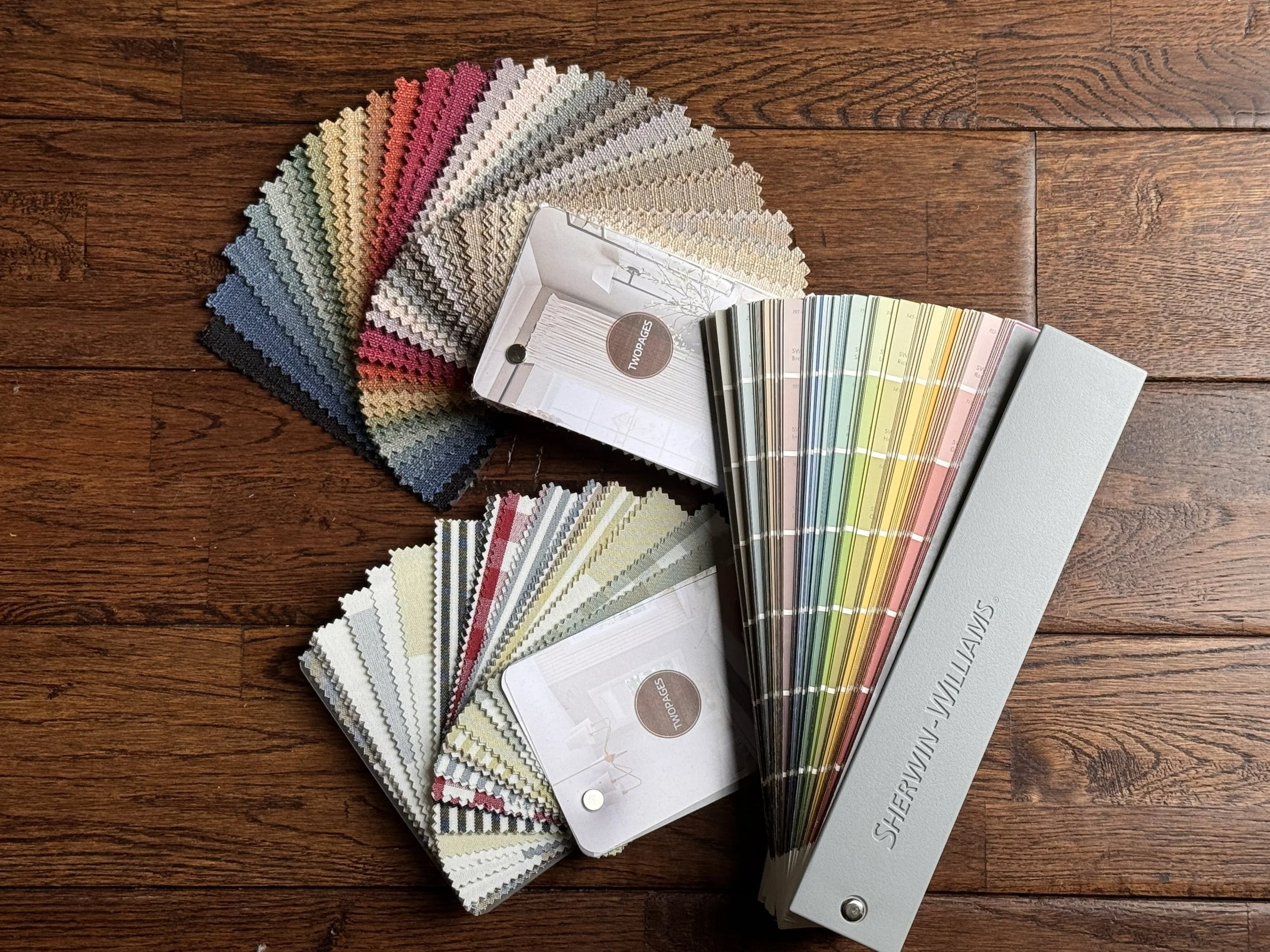 Fan decks of paint color samples in various shades arranged on a wooden surface.