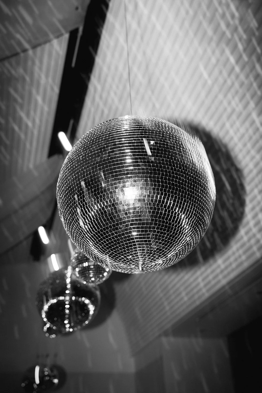 A disco ball hanging from the ceiling reflecting light, with several smaller disco balls visible in the background.