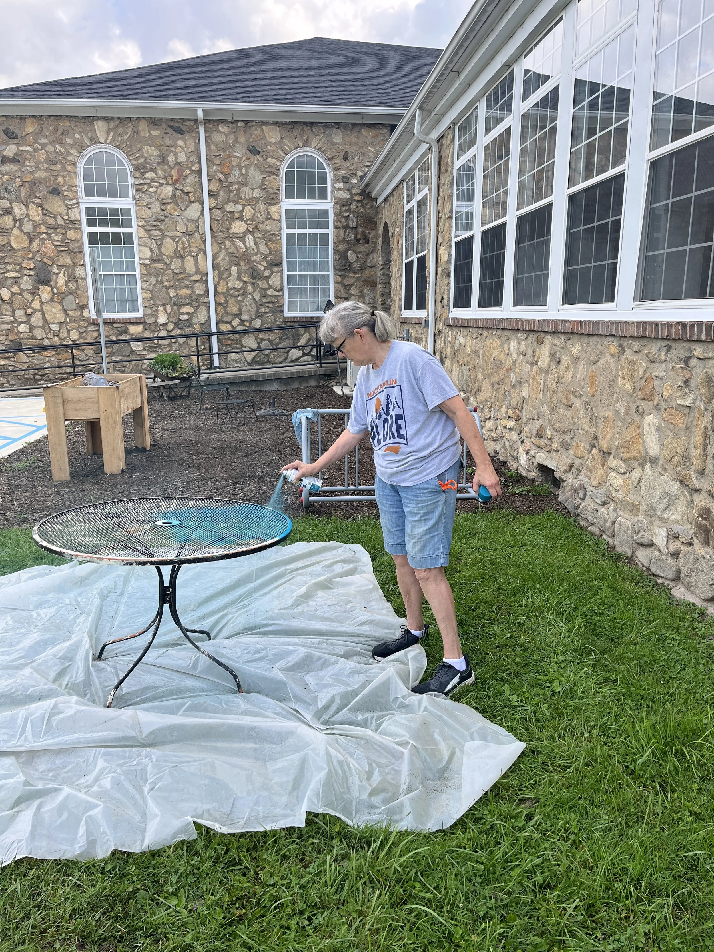 2026 - A volunteer helps by painting the outdoor table. 