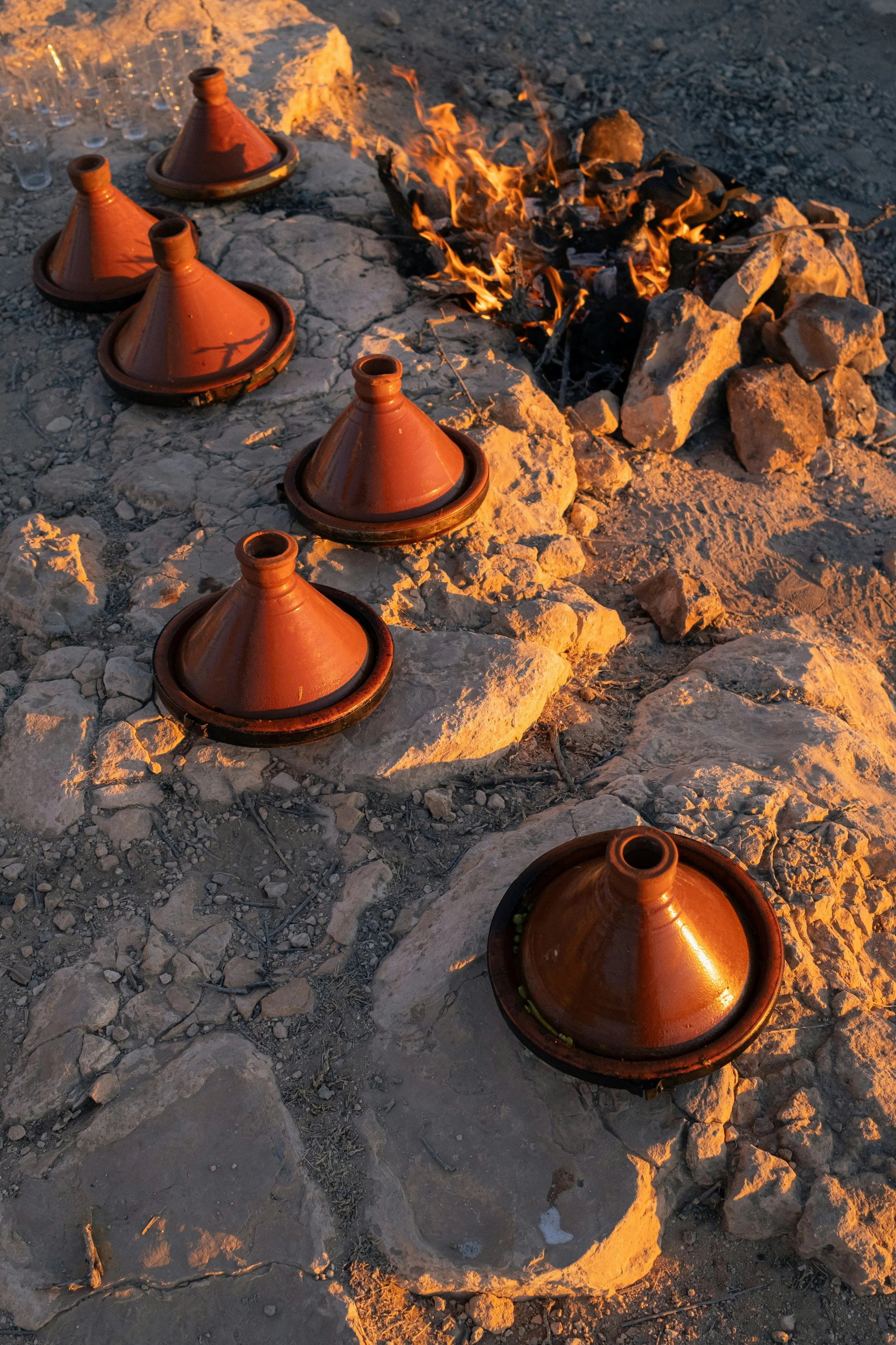 Traditional Moroccan tagine cookware set around a campfire.