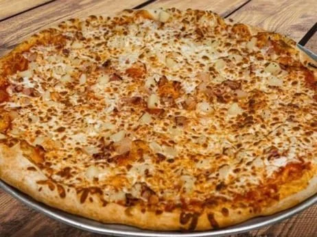 Large cheese pizza with some toppings on a metal tray on a wooden table.