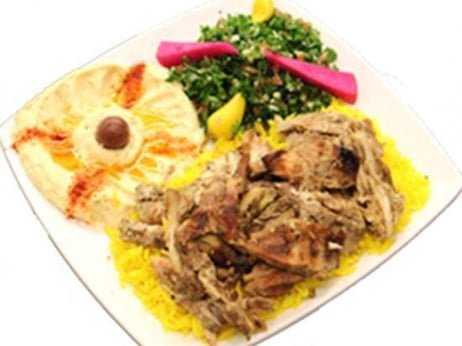 Plate with cooked lamb, yellow rice, salad with greens, chopped vegetables, and pickled radish.