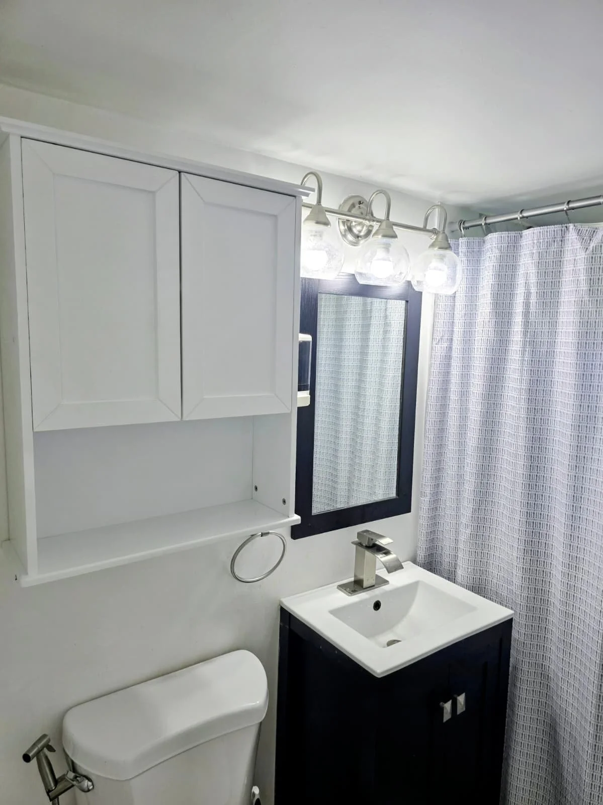 Bathroom with a white wall-mounted cabinet,assembled and installed by sian home services.Concrete wall was repaired behind the toilet by sian home services