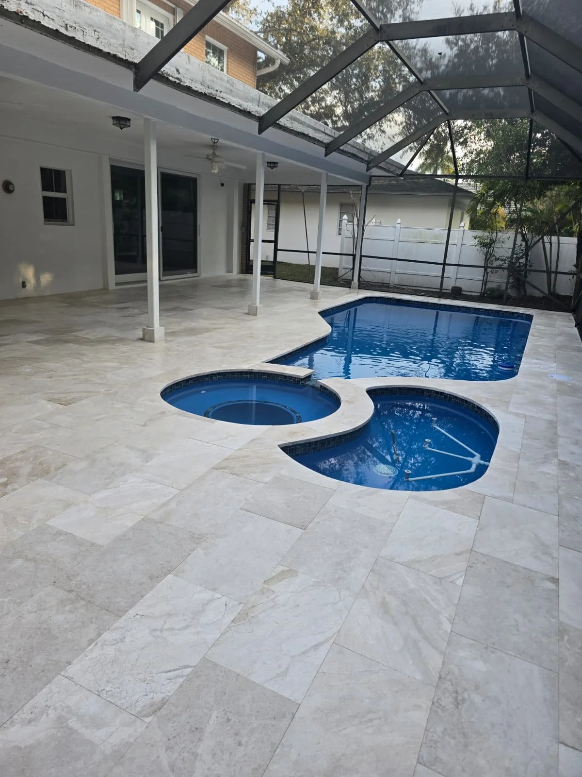 Backyard with a swimming pool, hot tub, and a screened enclosure. There is a porch with ceiling lights and a ceiling fan.