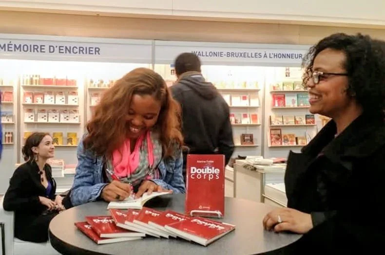 Martine Fidèle dédicaçant son roman Double corps à une lectrice lors d'une séance de signatures.