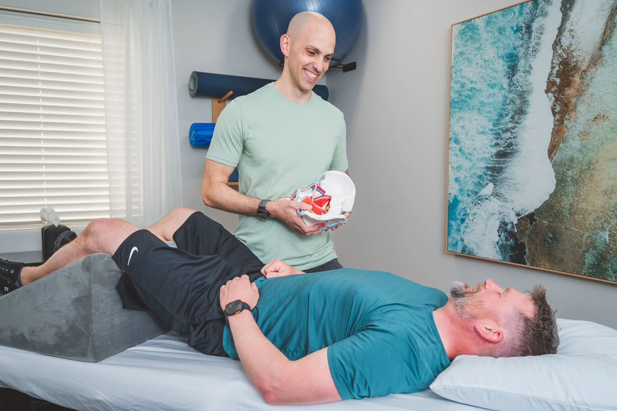 pelvic therapist demoing on a pelvic model for a male patient