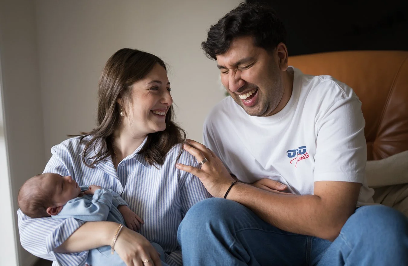 Newborn baby resting in a parent’s lap during a relaxed in-home newborn photography session with both parents in Bayside,Melbourne.