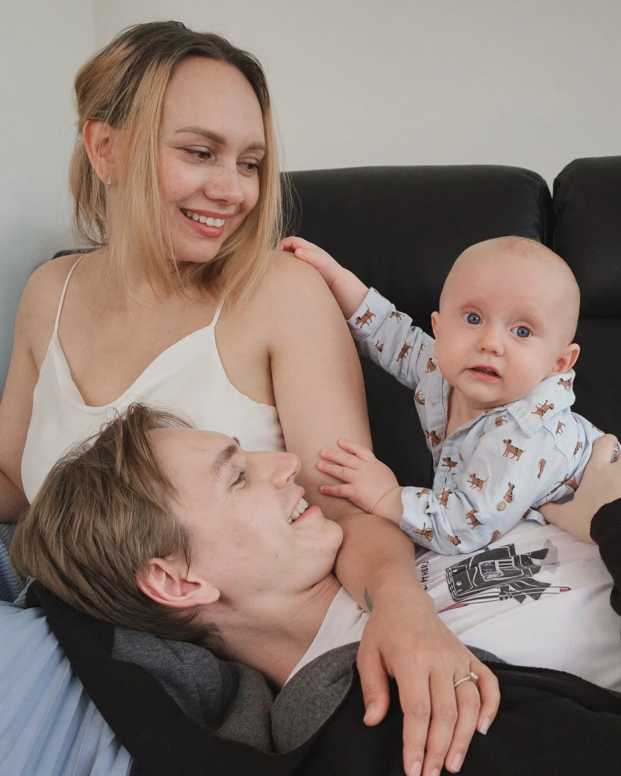 Lifestyle baby photography in Melbourne featuring parents cuddling their smiling baby at home. Natural family photography capturing genuine connection, love and everyday moments during the first year.