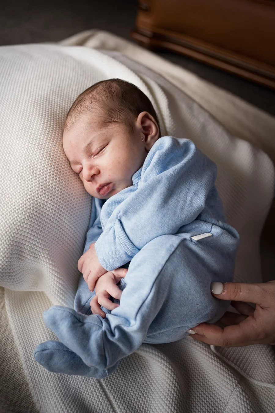 A sleeping newborn baby curled up on a soft blanket during an in-home newborn photography session in Bentleigh, Melbourne.