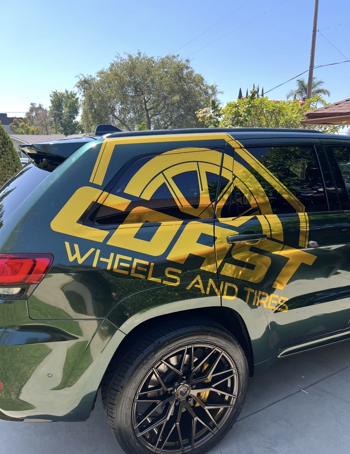 A black SUV with a yellow graphic logo on the side that reads "Wheels" and "Wheels and Tires".
