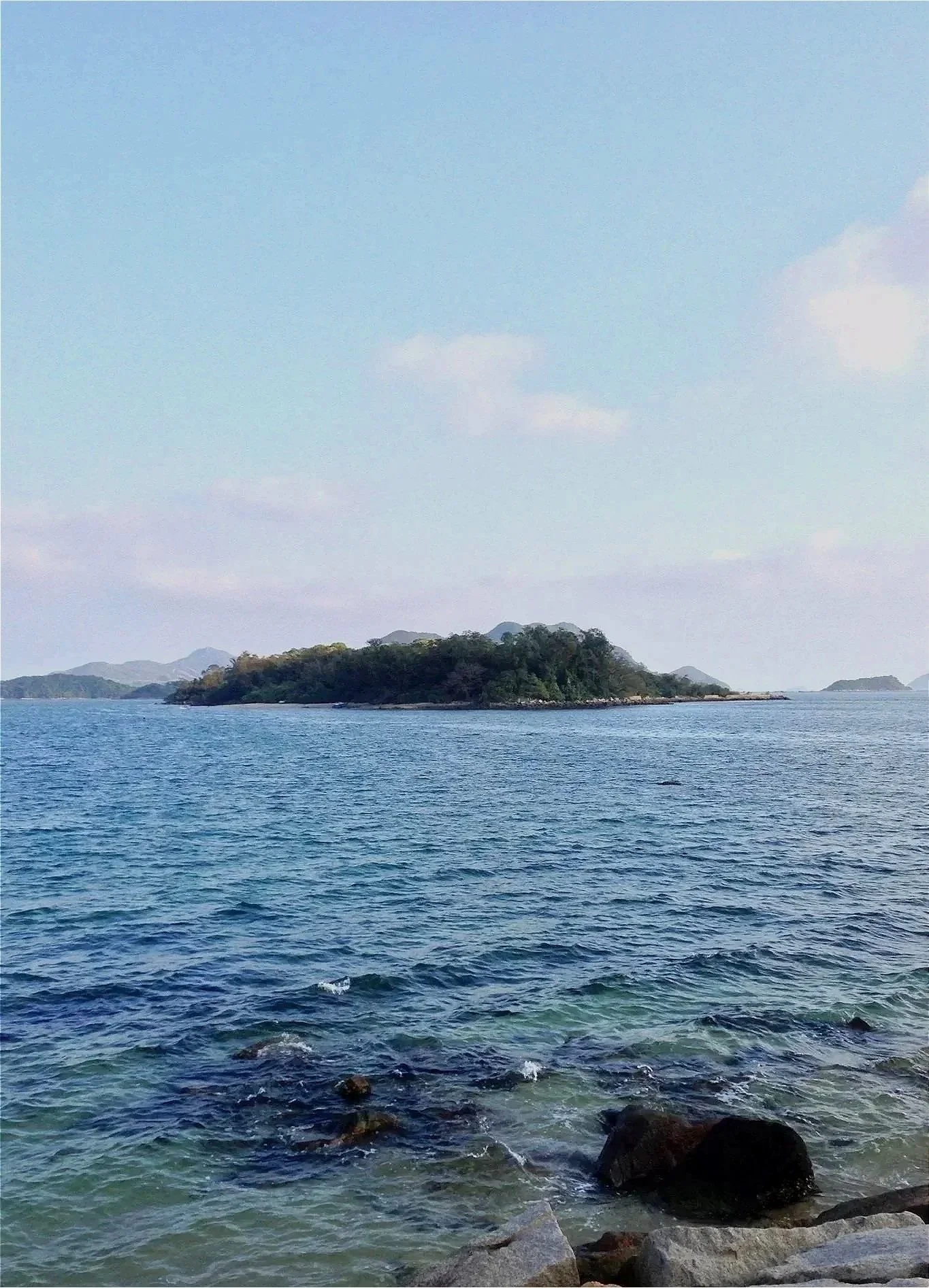 View across calm blue water toward a small island under an open sky, symbolizing hope and healing from trauma.