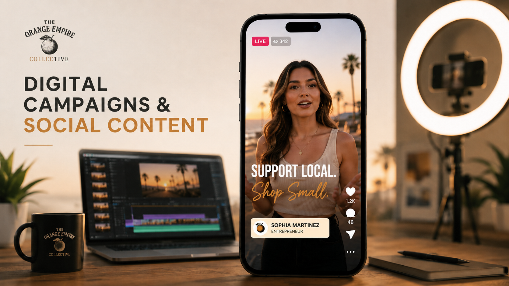 A promotional display for The Orange Empire Collective featuring digital campaigns and social content. In the foreground, a smartphone shows a live video of a woman, Sophia Martinez, promoting supporting local businesses and shopping small, with palm trees in the background. Behind the phone, a laptop with video editing software, a black mug with the logo, an open notebook, and a ring light are visible in a cozy, well-lit workspace.