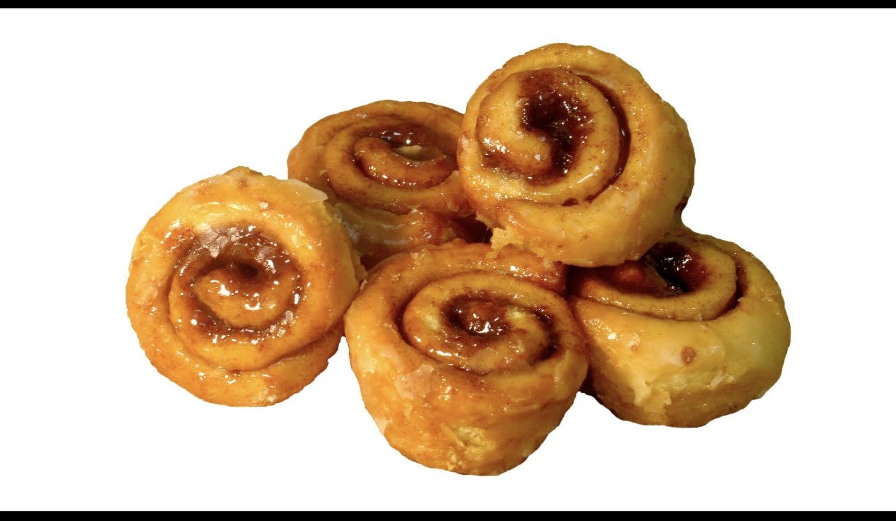 Six cinnamon rolls with icing and caramelized topping, arranged on a white background.