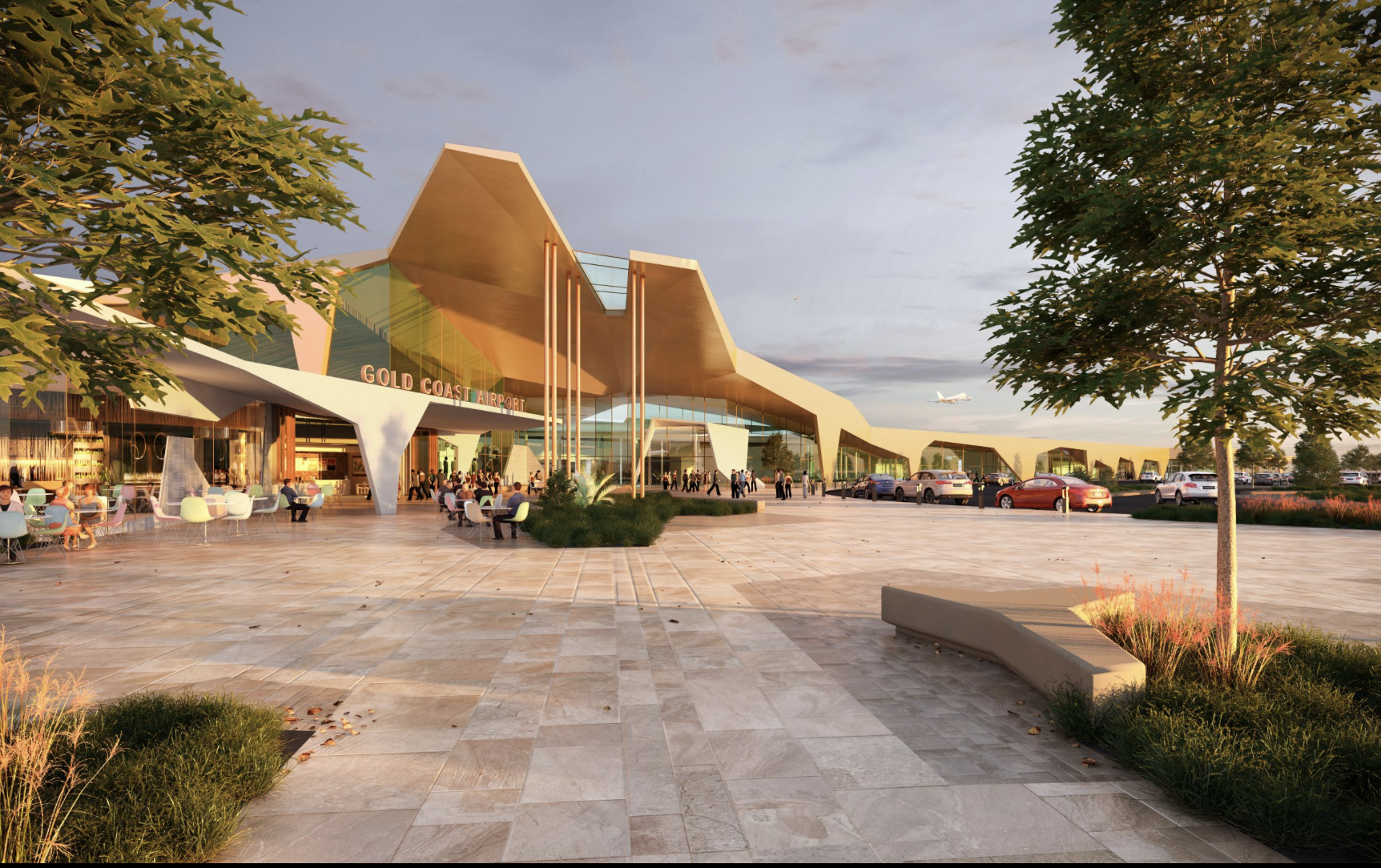 Modern architecture of Gold Coast Airport terminal with people walking, sitting at outdoor seating, and arriving vehicles in parking lot, with trees and landscaped areas, airplanes taking off in the background at sunset.