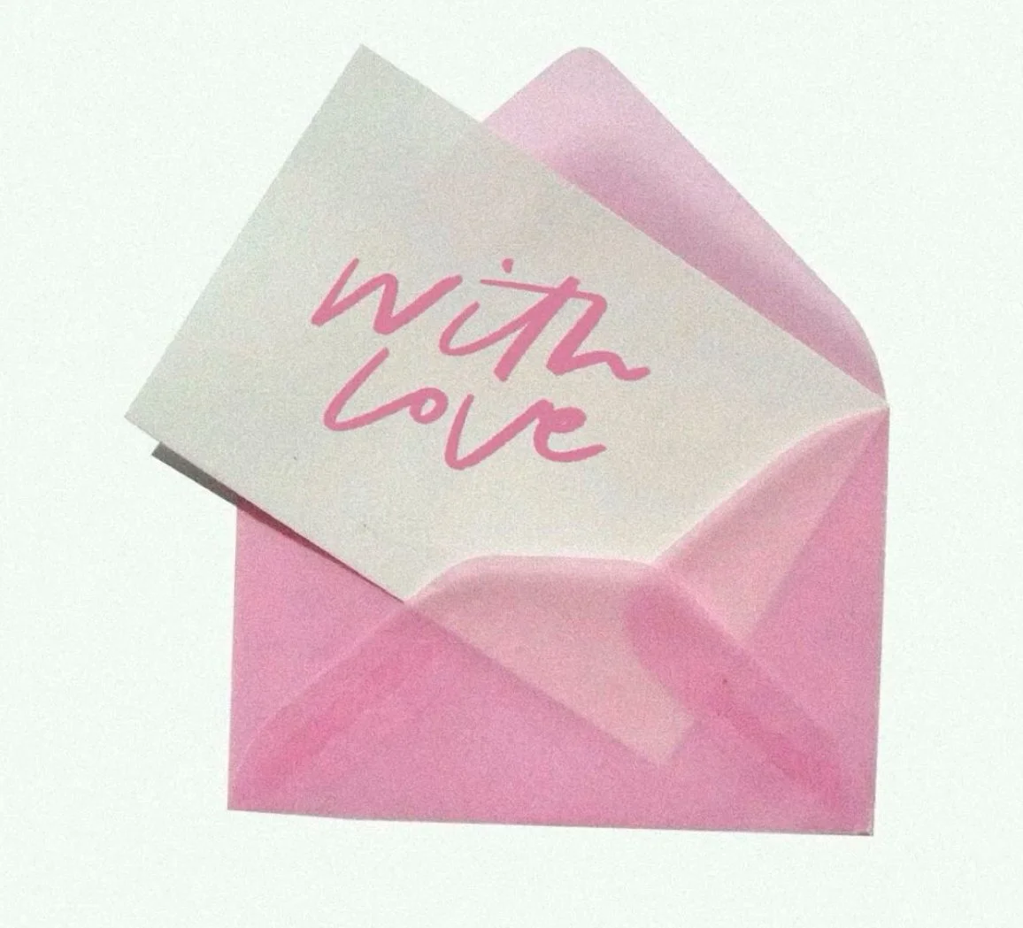 Pink paper envelope with a white note inside that reads 'with love' in pink handwriting.