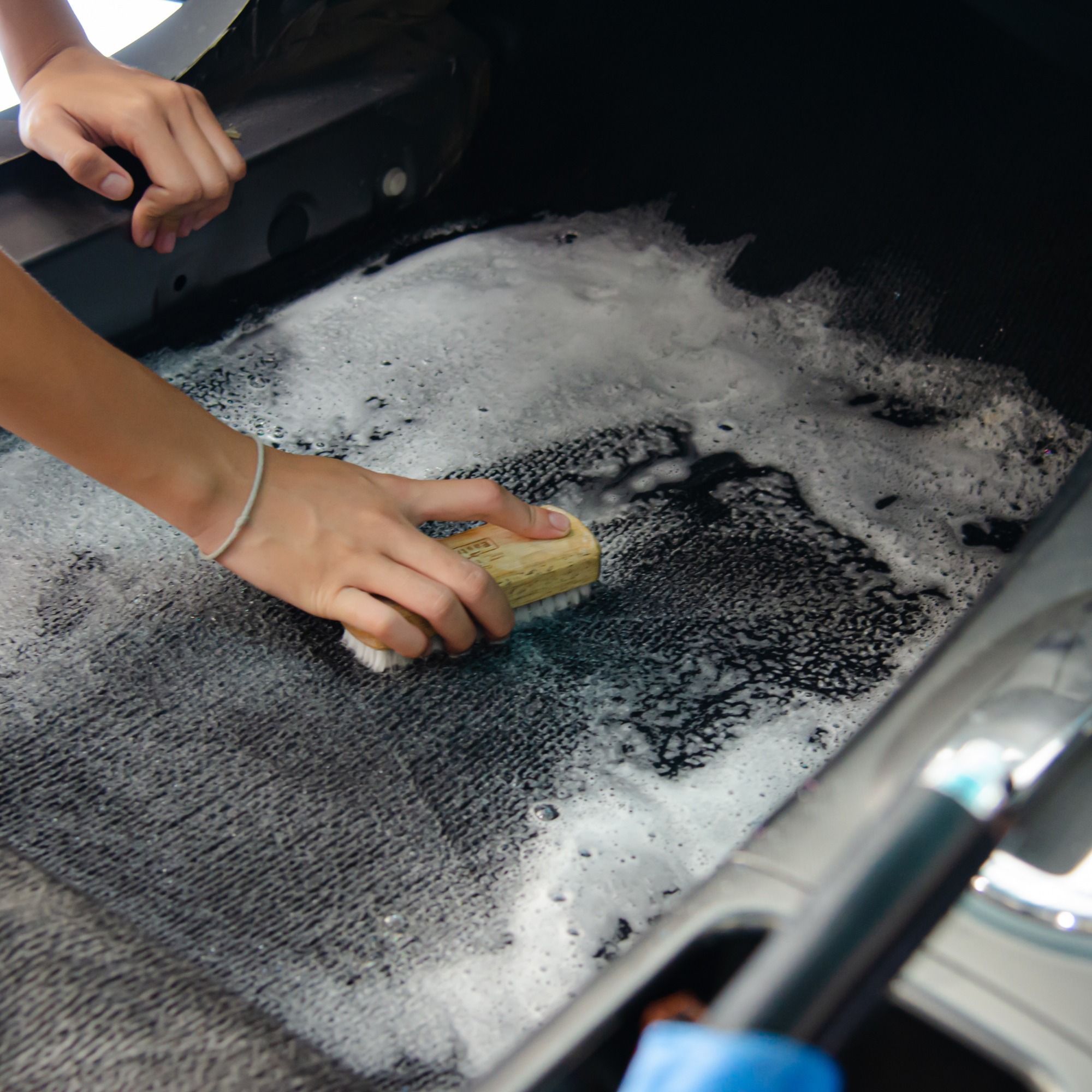 A person is scrubbing the tire of a car with a brush.