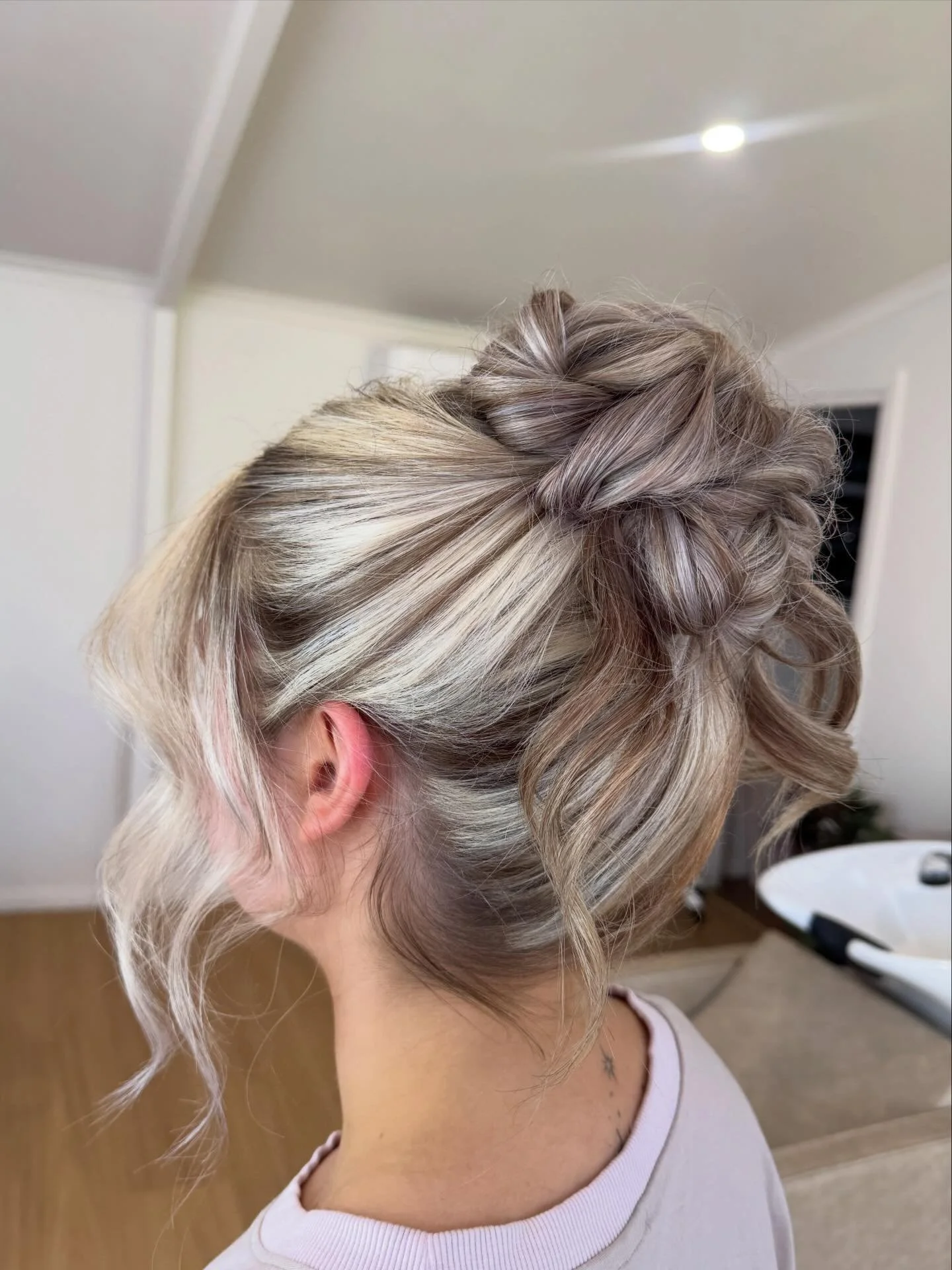 A woman with blonde hair styled in an elegant updo with voluminous curls at the back.