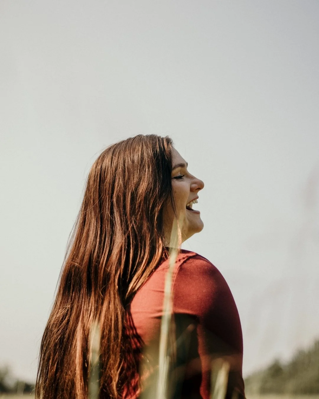 Woman in red shirt with long brown hair laughing