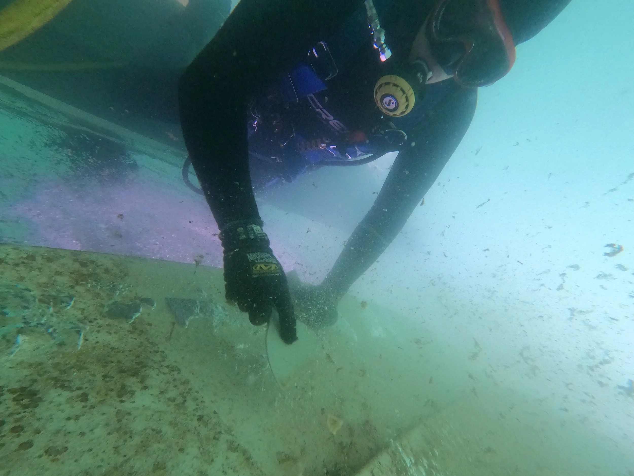 Underwater commercial professional scuba diver conducting hull cleaning and underwater vessel and boat maintenance.