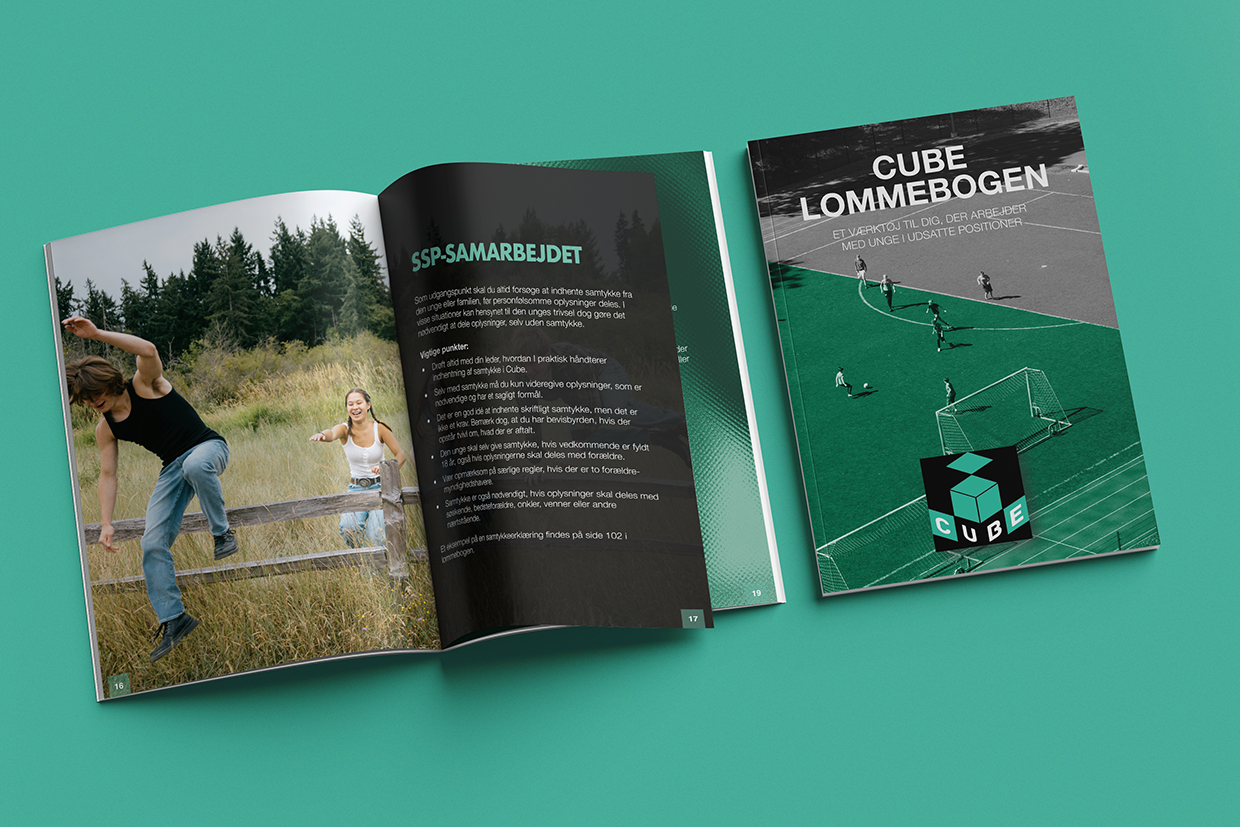 En åben bog med et cover, der viser en fodboldbane med spillere. En anden bog er åben og viser et layout med tekst og en fotografi af to unge, der leger udenfor i naturen med en trælemmes