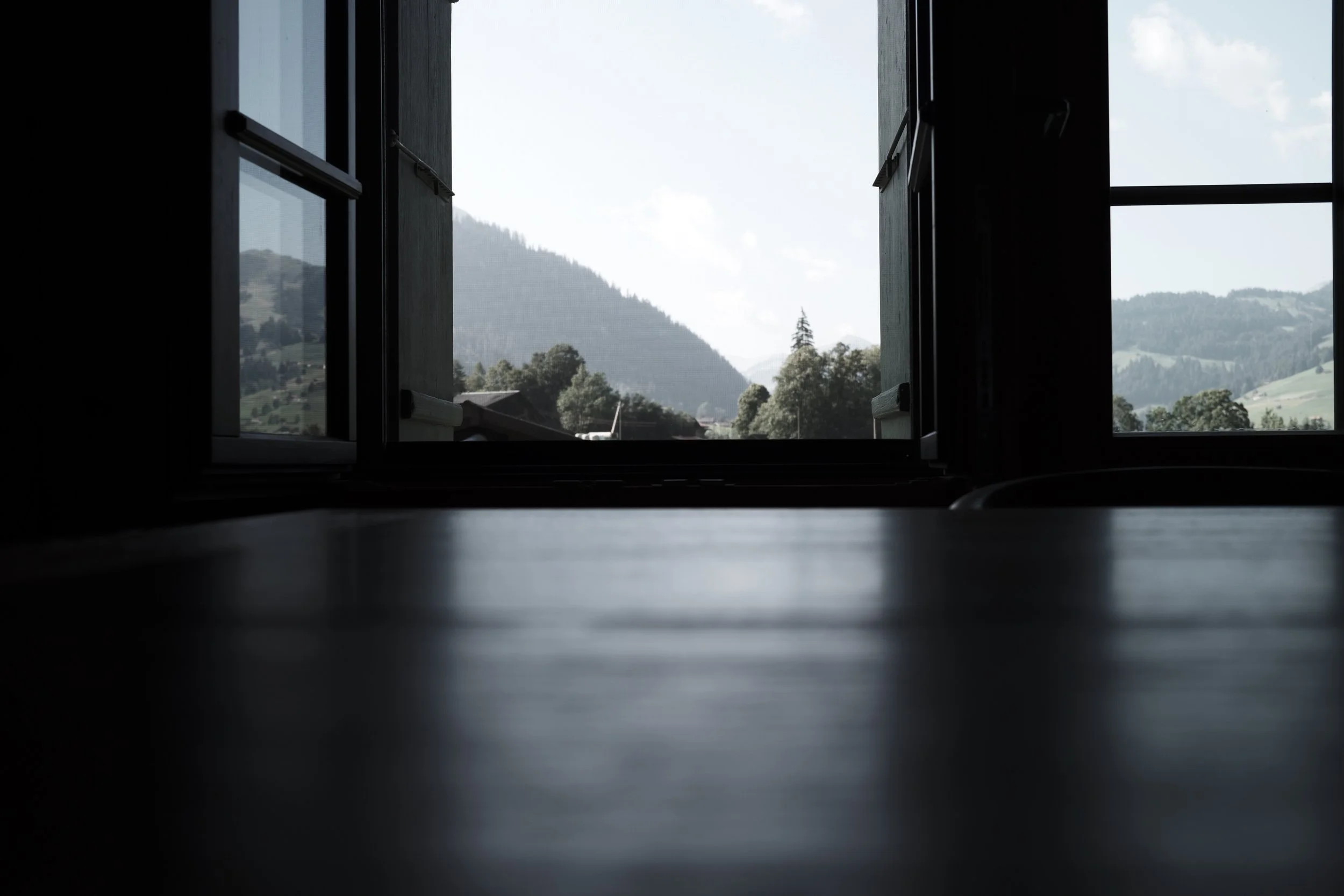 Open window with distant view of green hills and mountains, cloudy sky