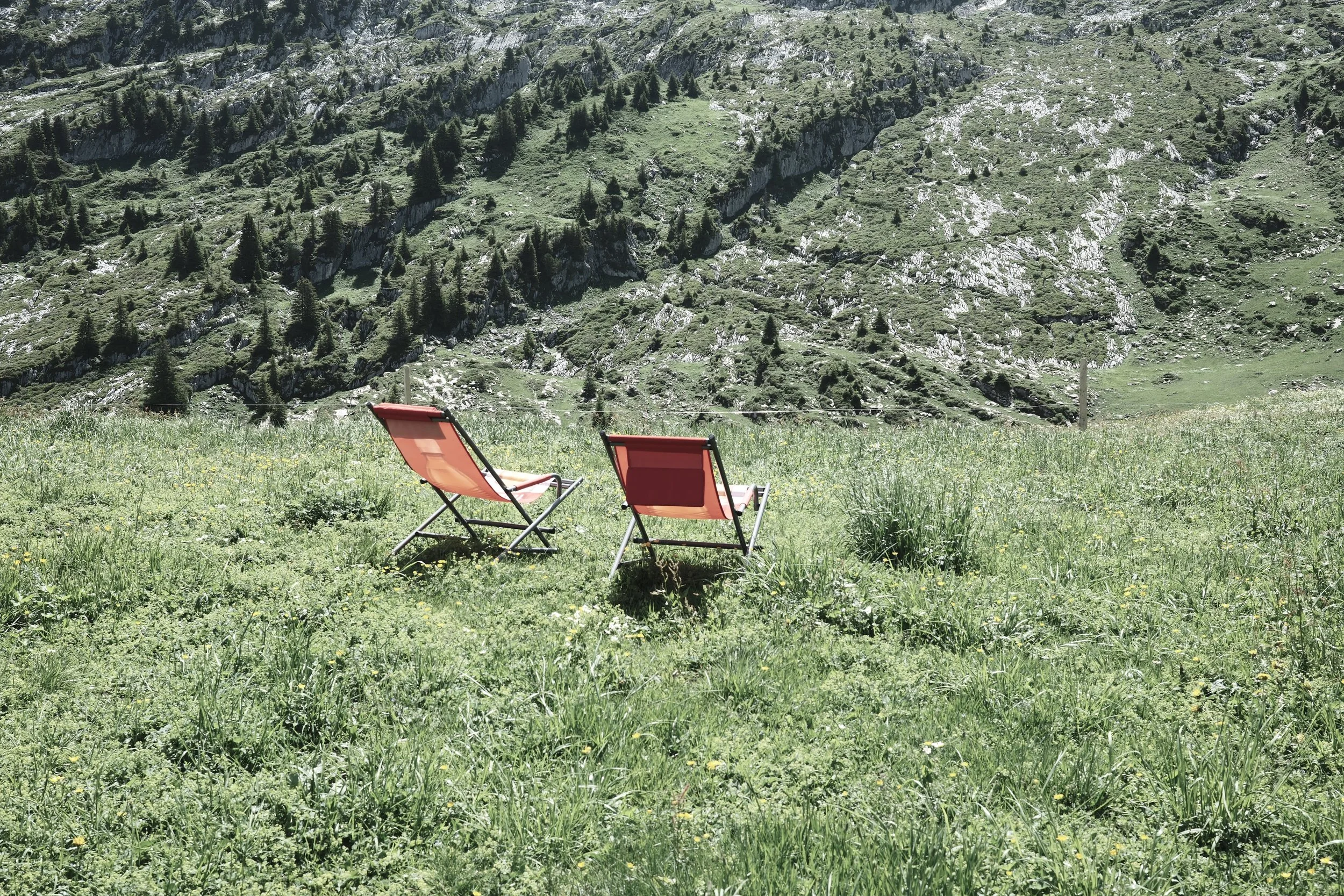 Two deck chairs overlooking an alpine meadow in the Bernese Oberland near Gstaad, one of the quiet places recommended by Haus Mannenberg.