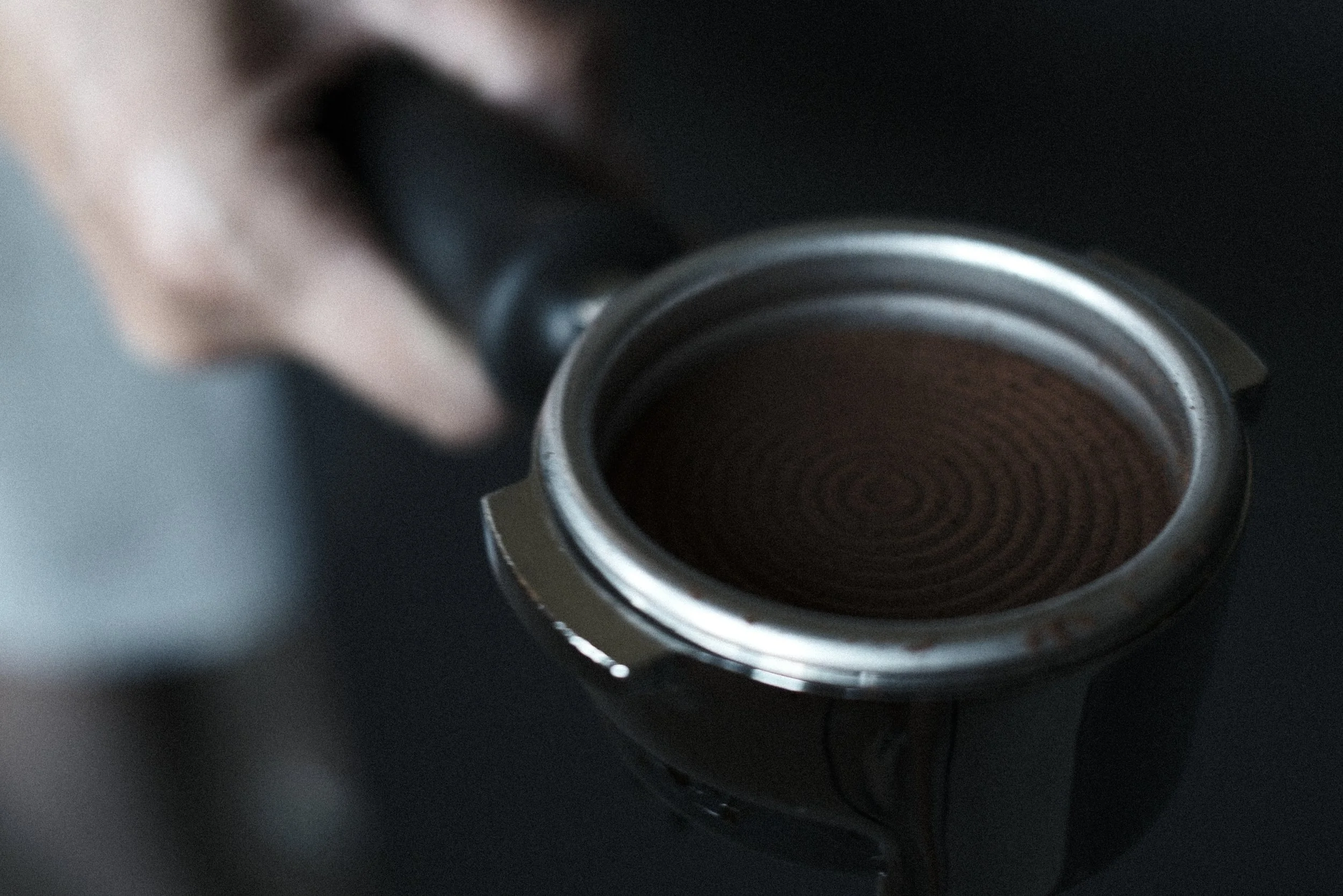 Close-up of a metallic espresso coffee cup filled with dark coffee, on a dark surface.