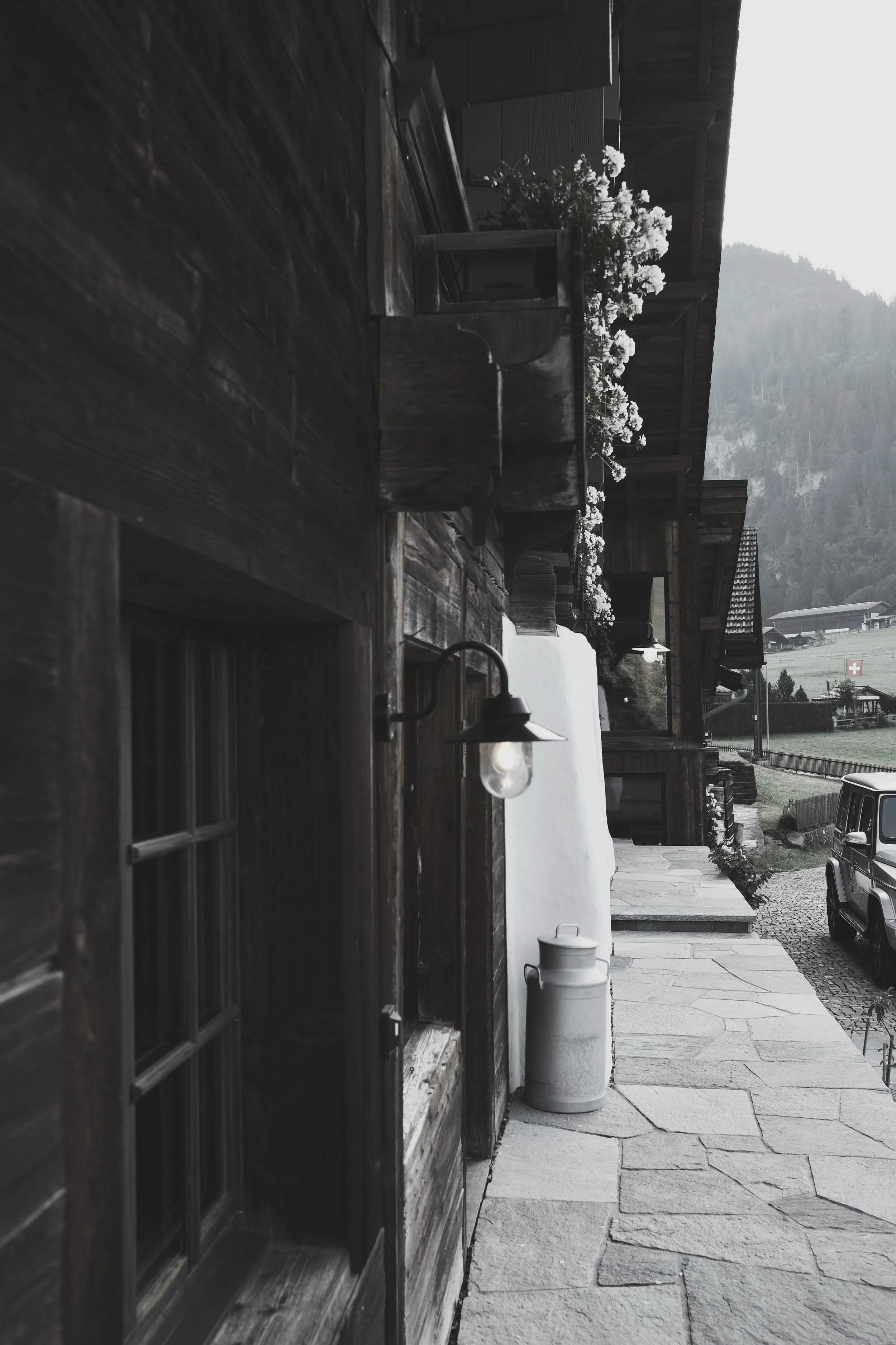 Historic entrance of Haus Mannenberg with original timber façade, traditional Swiss architecture and natural stone walkway in Mannried near Gstaad.
