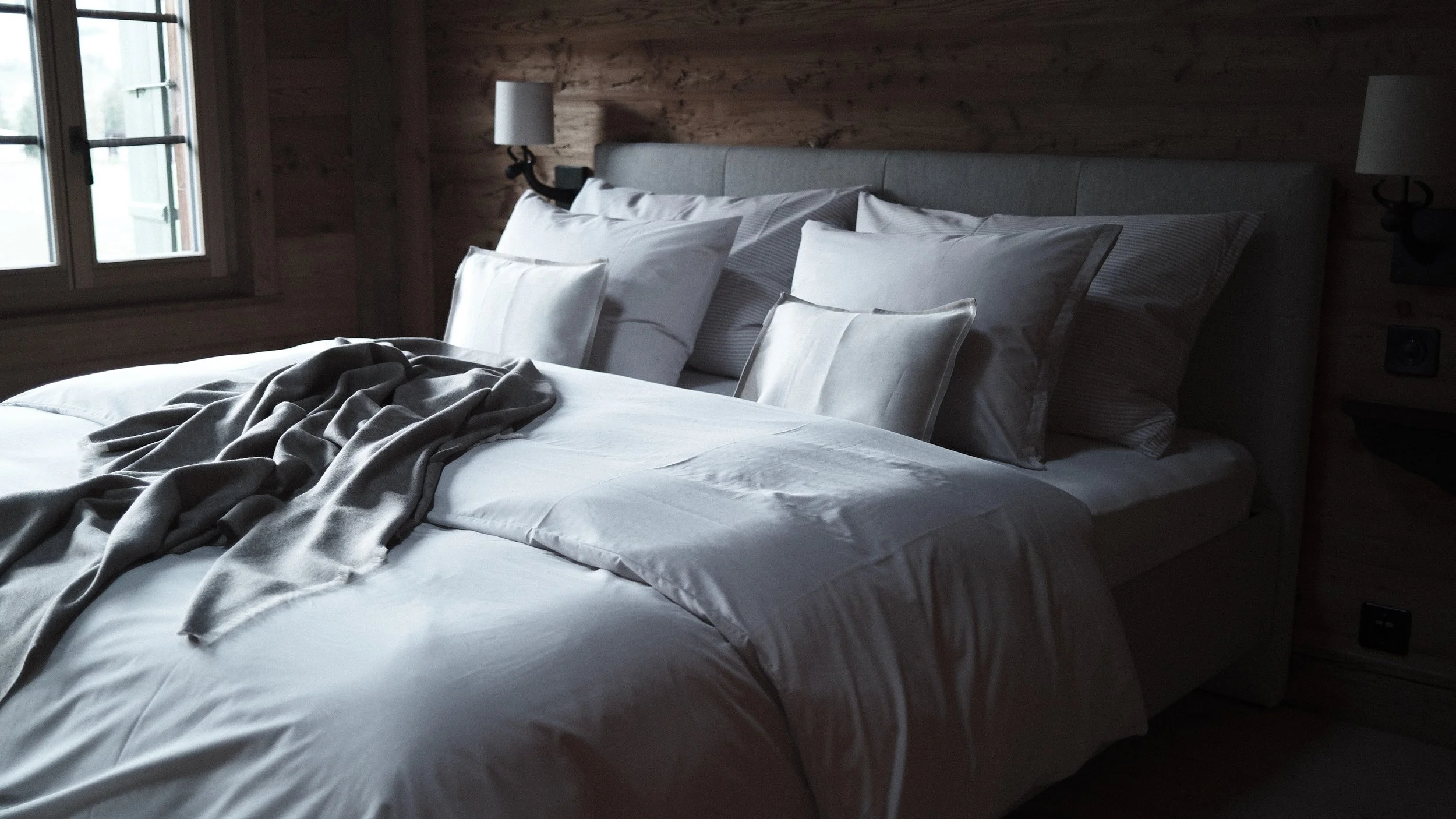 Alt text Historic guest room at Haus Mannenberg with Schlossberg bed linen, original timber walls and views across the Bernese Oberland.