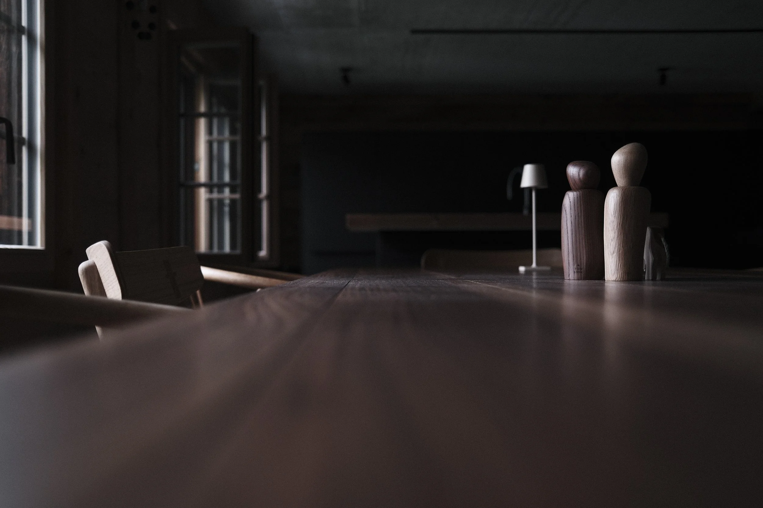 Historic communal table at Haus Mannenberg with handcrafted wooden figures, original timber interior and soft morning light.